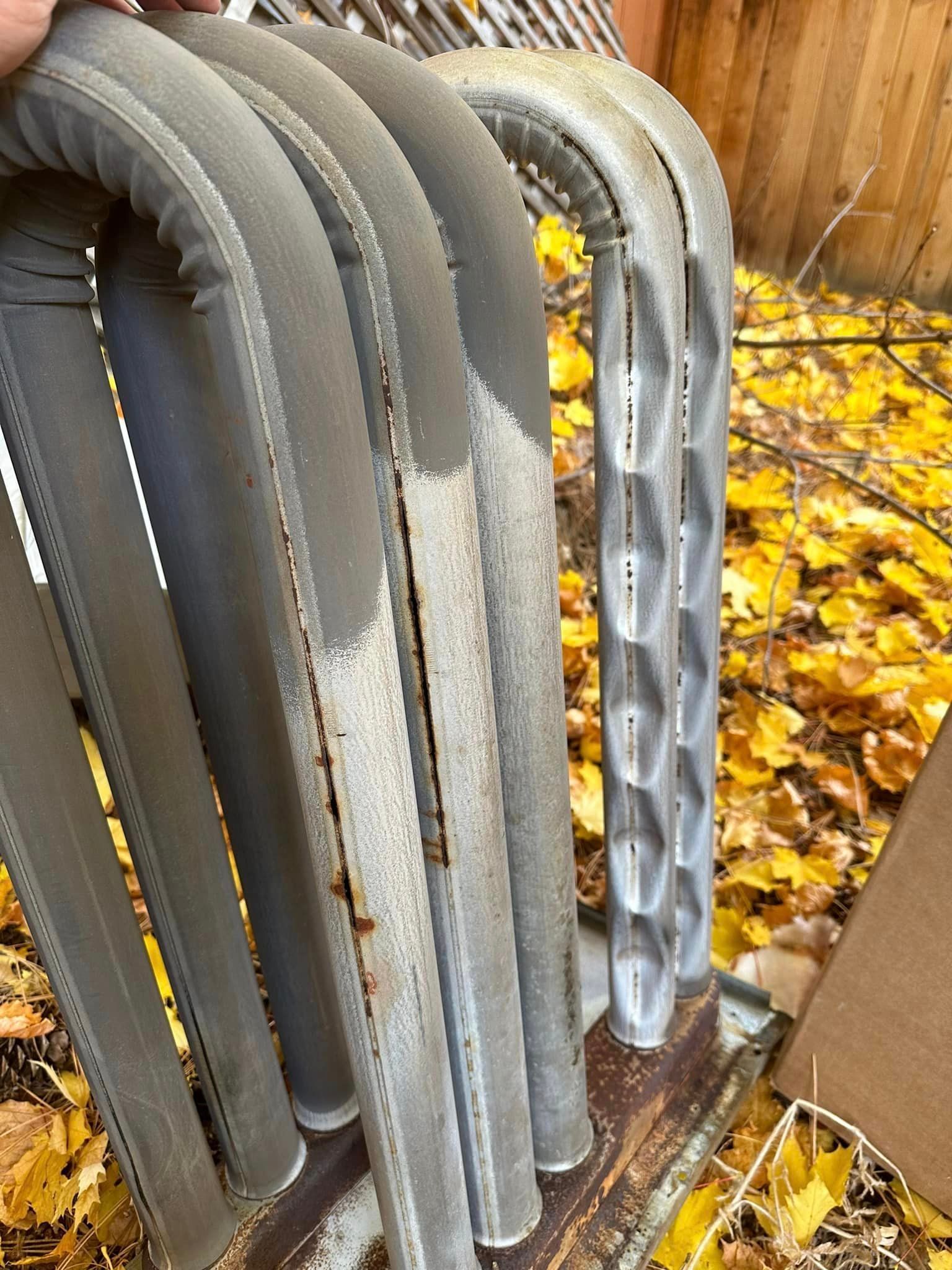 A person is holding a bunch of metal pipes in a pile of leaves.