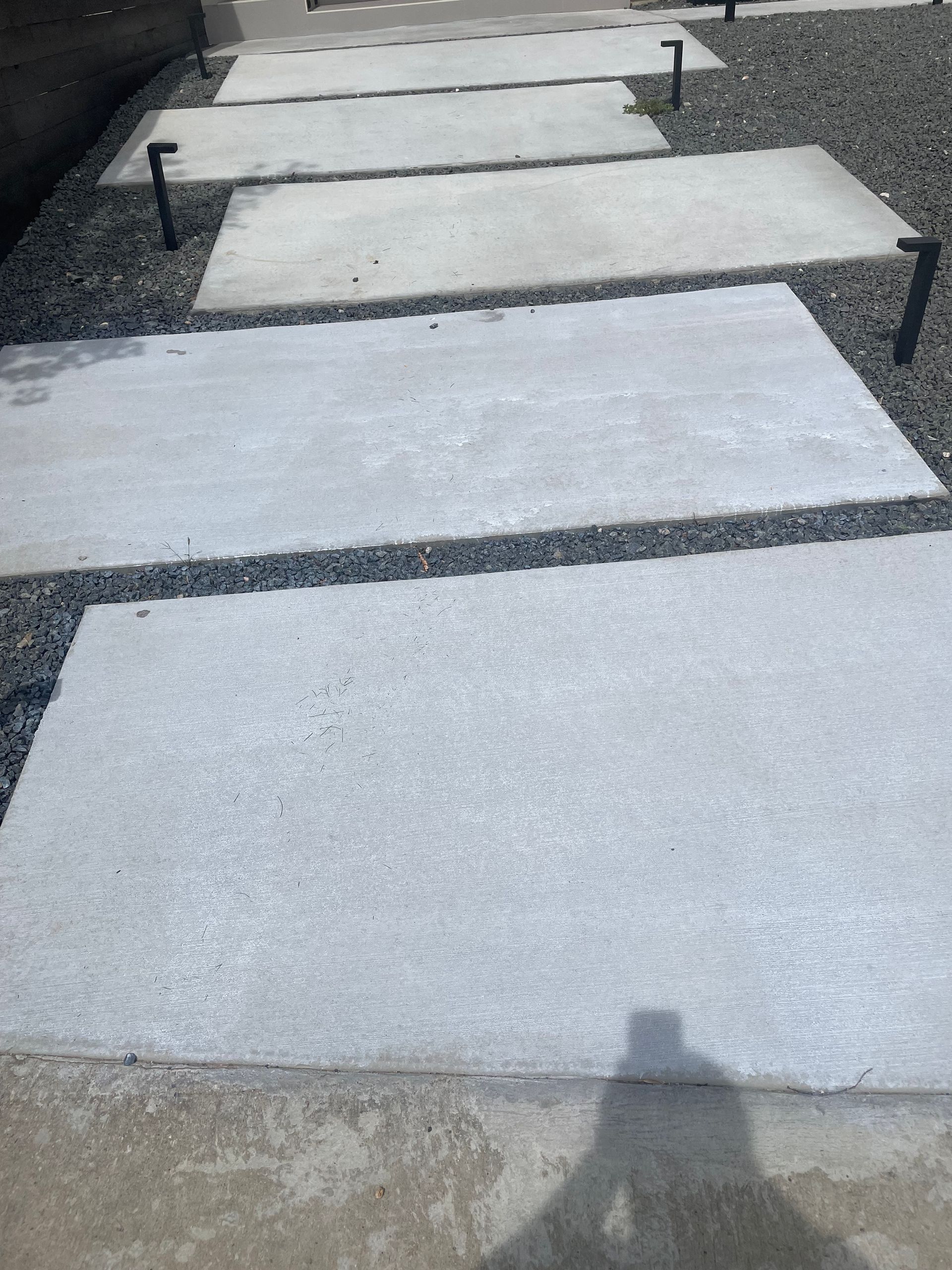 Concrete stepping stones in a gravel path, leading away outdoors.