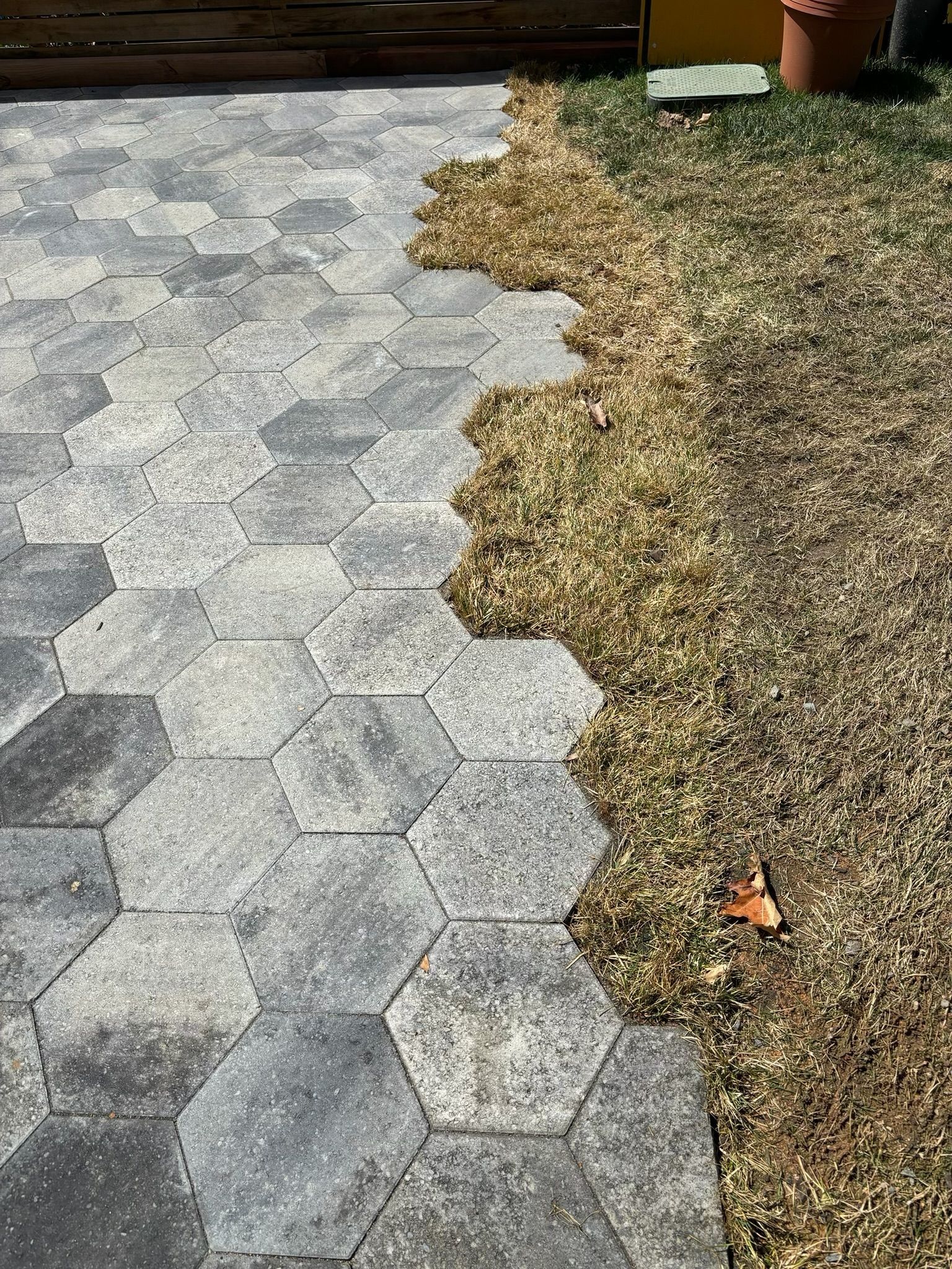 Hex paver walkway beside a brown gravel bed, with a wavy border between the two surfaces.