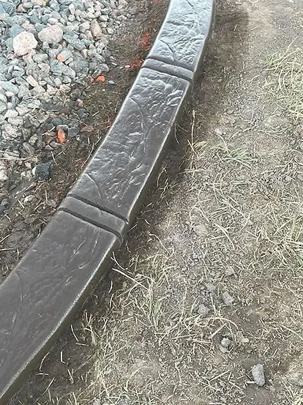Curved black curb edging beside gravel and patchy grass.