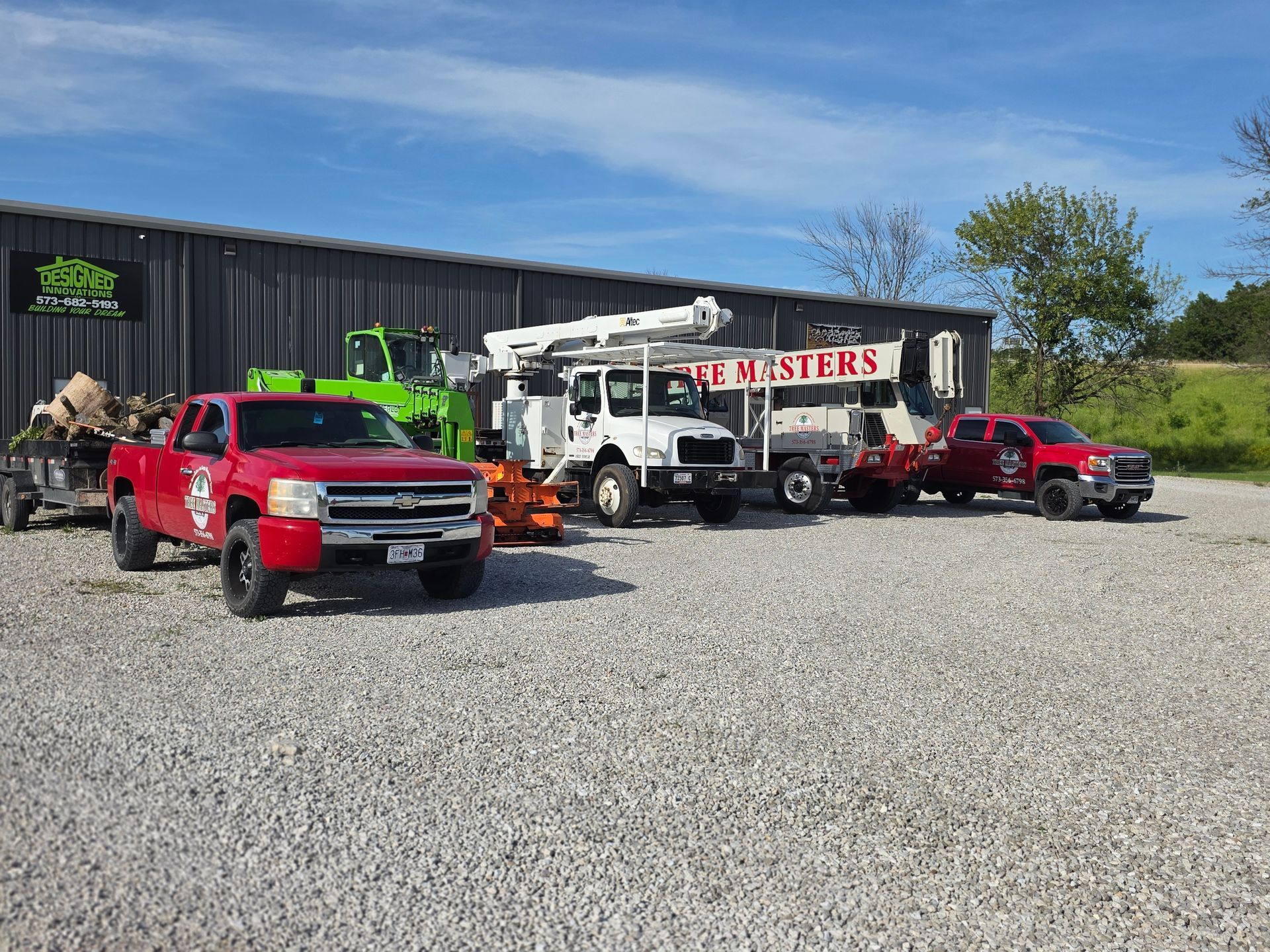 Red and white tow trucks parked on gravel outside a building with a large sign.