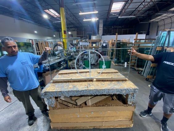 Two men are standing next to a wooden table in a warehouse