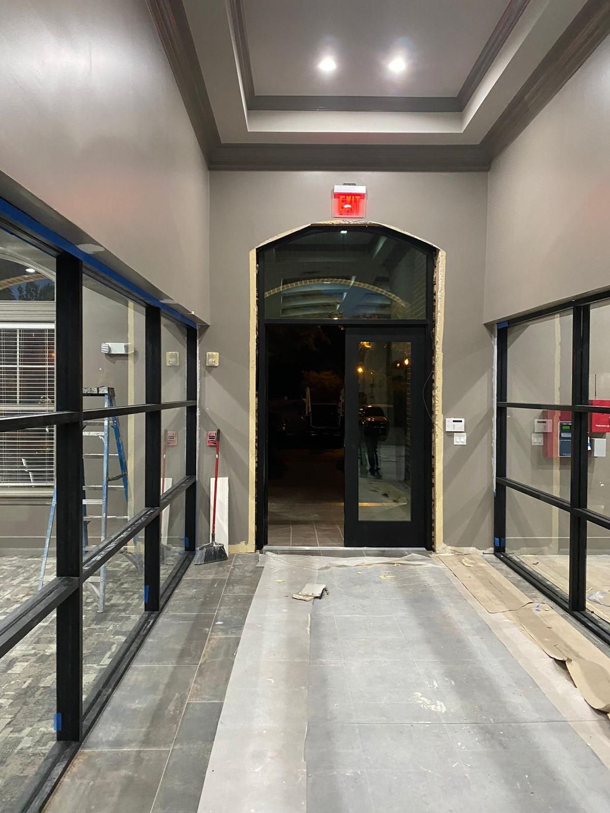 A hallway with a door and a red exit sign.