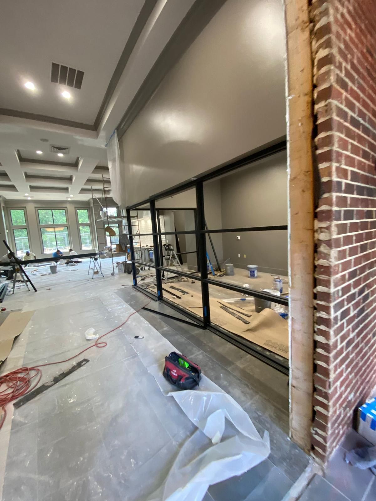 A large room with a brick wall and a lot of windows is being remodeled.