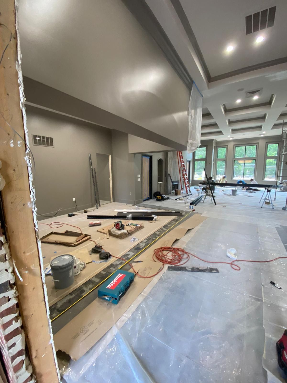 A large room is being remodeled with a lot of tools on the floor.