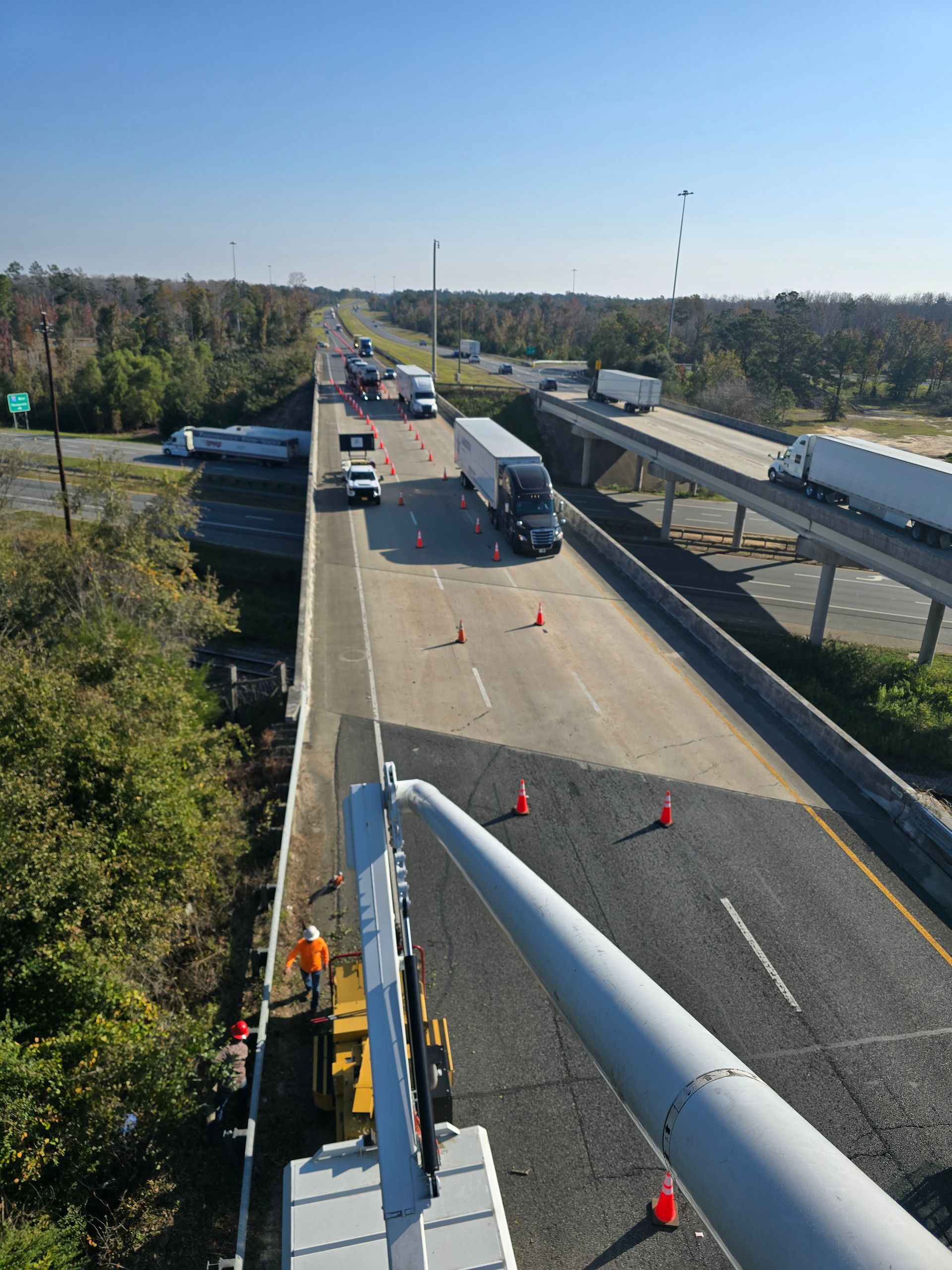 Highway overpass with traffic cones and trucks blocking lanes during roadwork