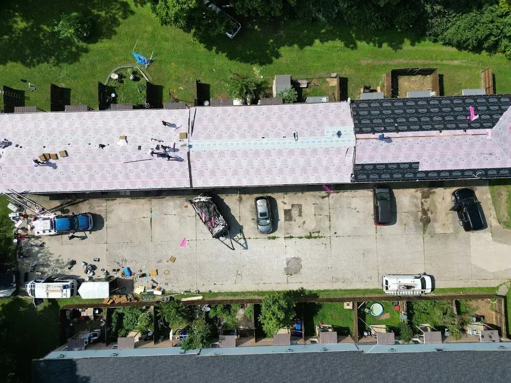 Aerial view of a street with parked cars beside buildings and trees.
