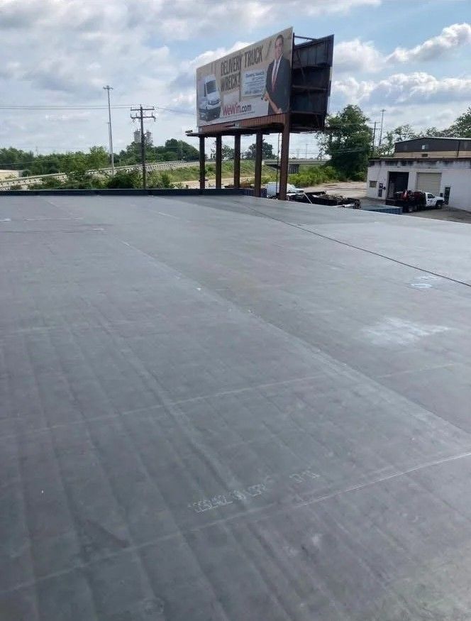 Empty rooftop with a large billboard and a small utility building under a cloudy sky.