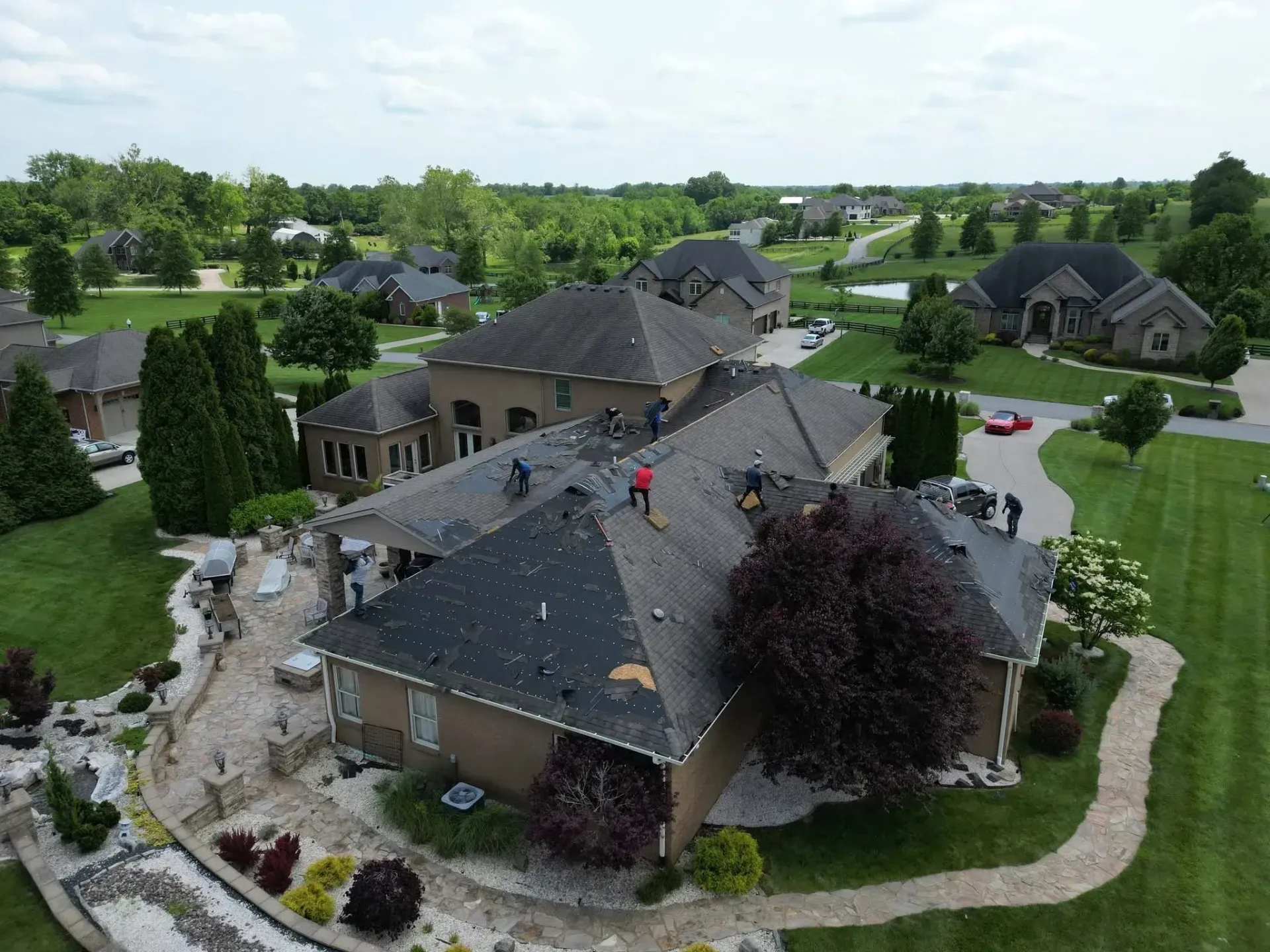 Aerial view of a suburban neighborhood with houses, trees, and winding roads on a sunny day