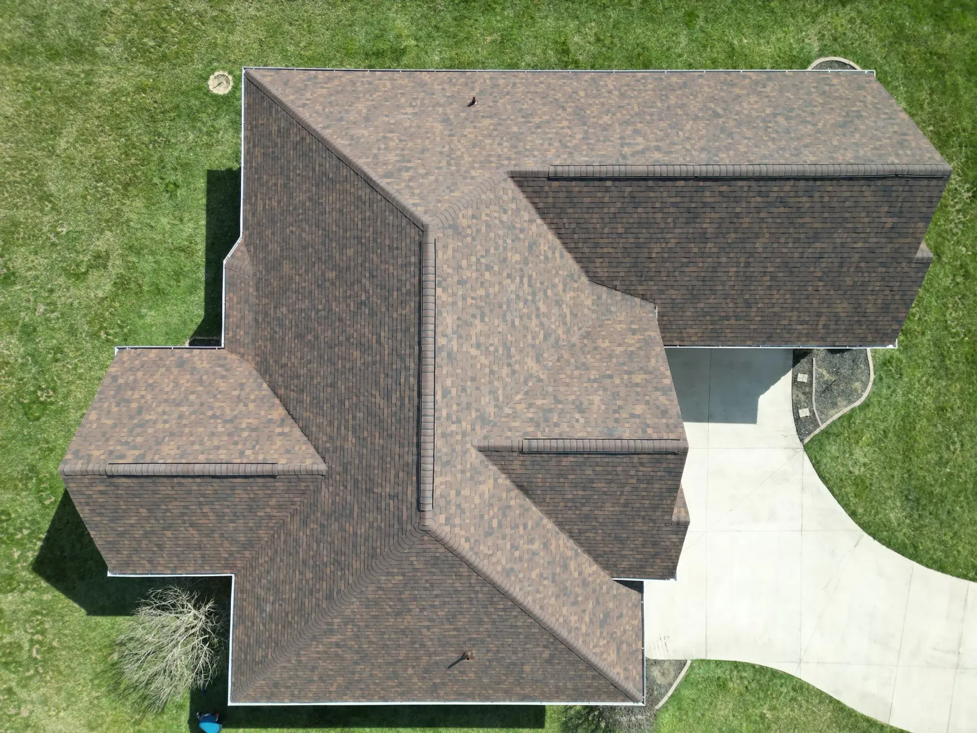 Aerial view of a gray-roofed house with a driveway and green lawn.