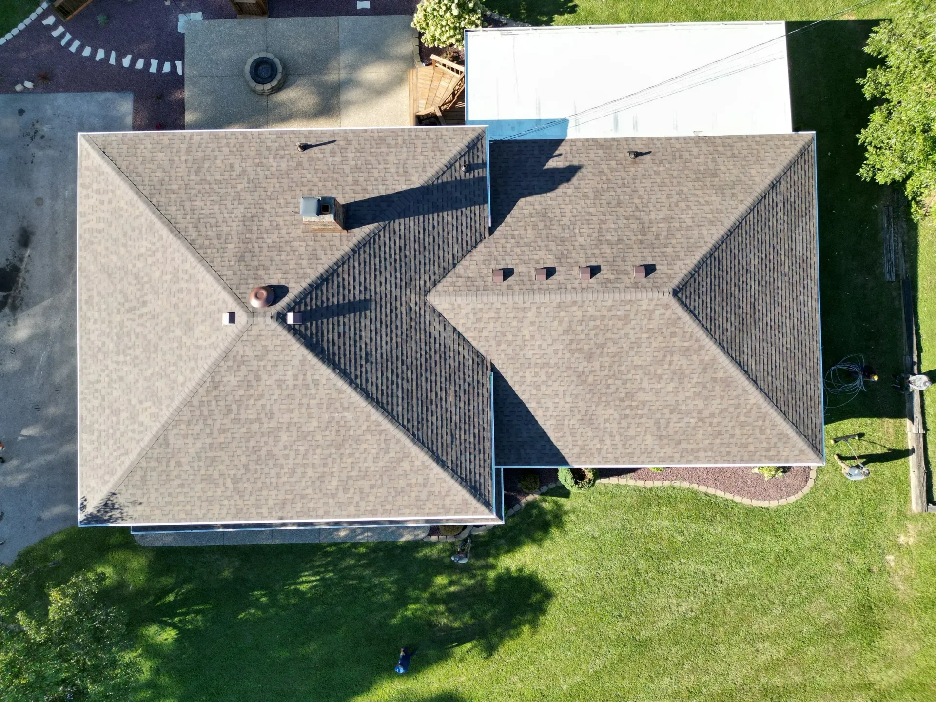 Aerial view of a house with a gray shingle roof and green lawn around it.