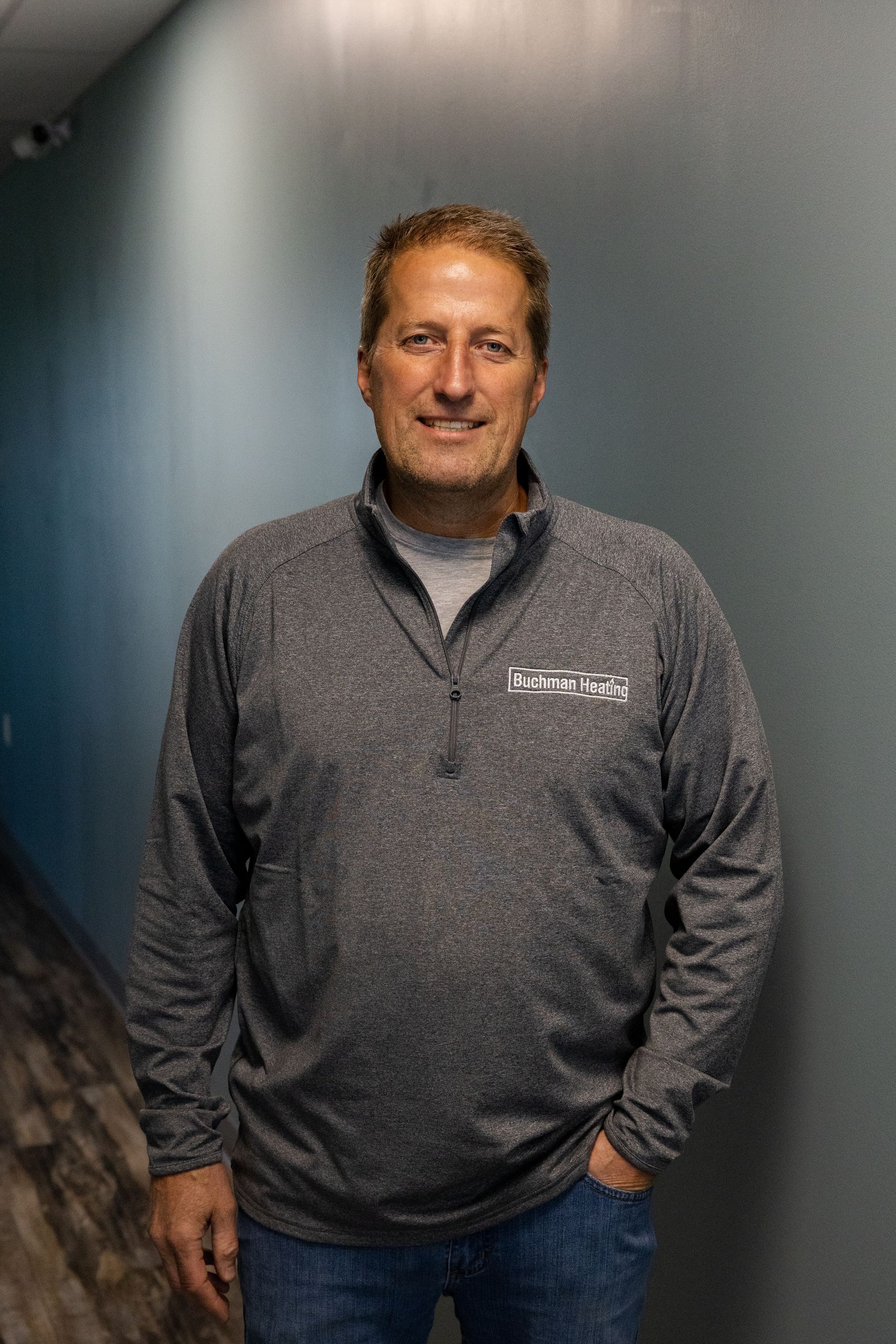 A man is standing in a hallway with his hands in his pockets.