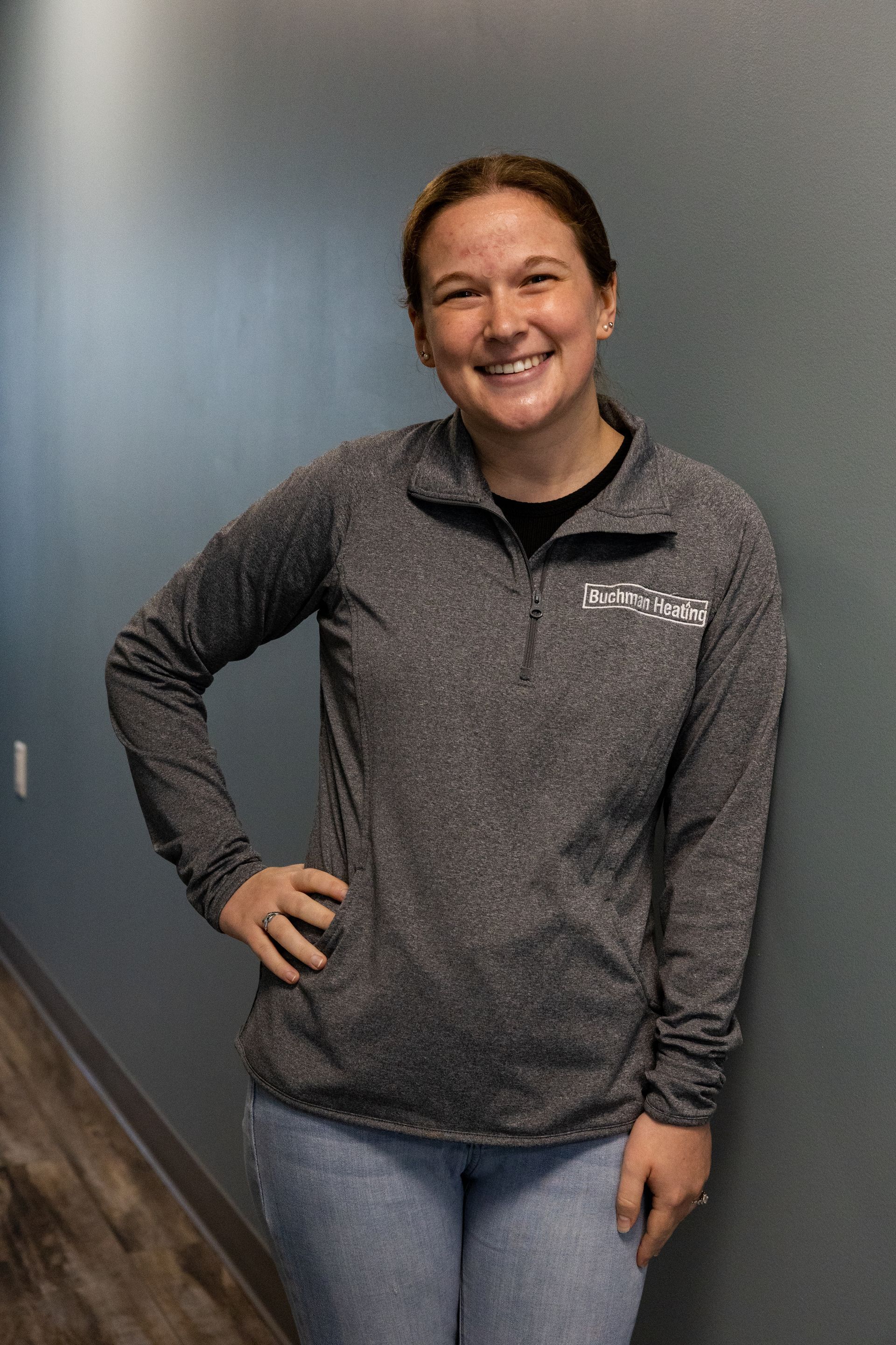 A woman is standing in a hallway with her hands on her hips and smiling.