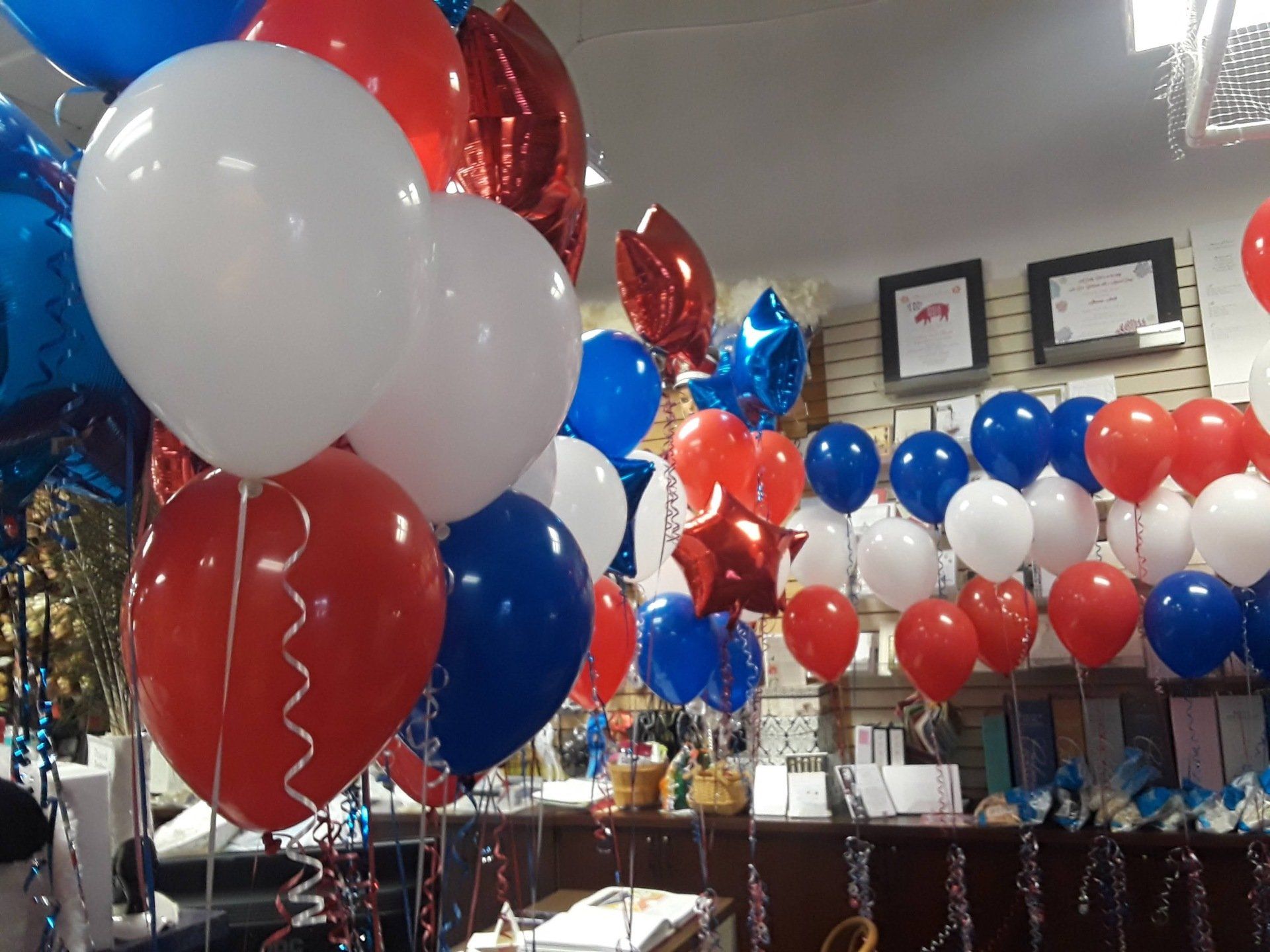 A bunch of red white and blue balloons hanging from the ceiling