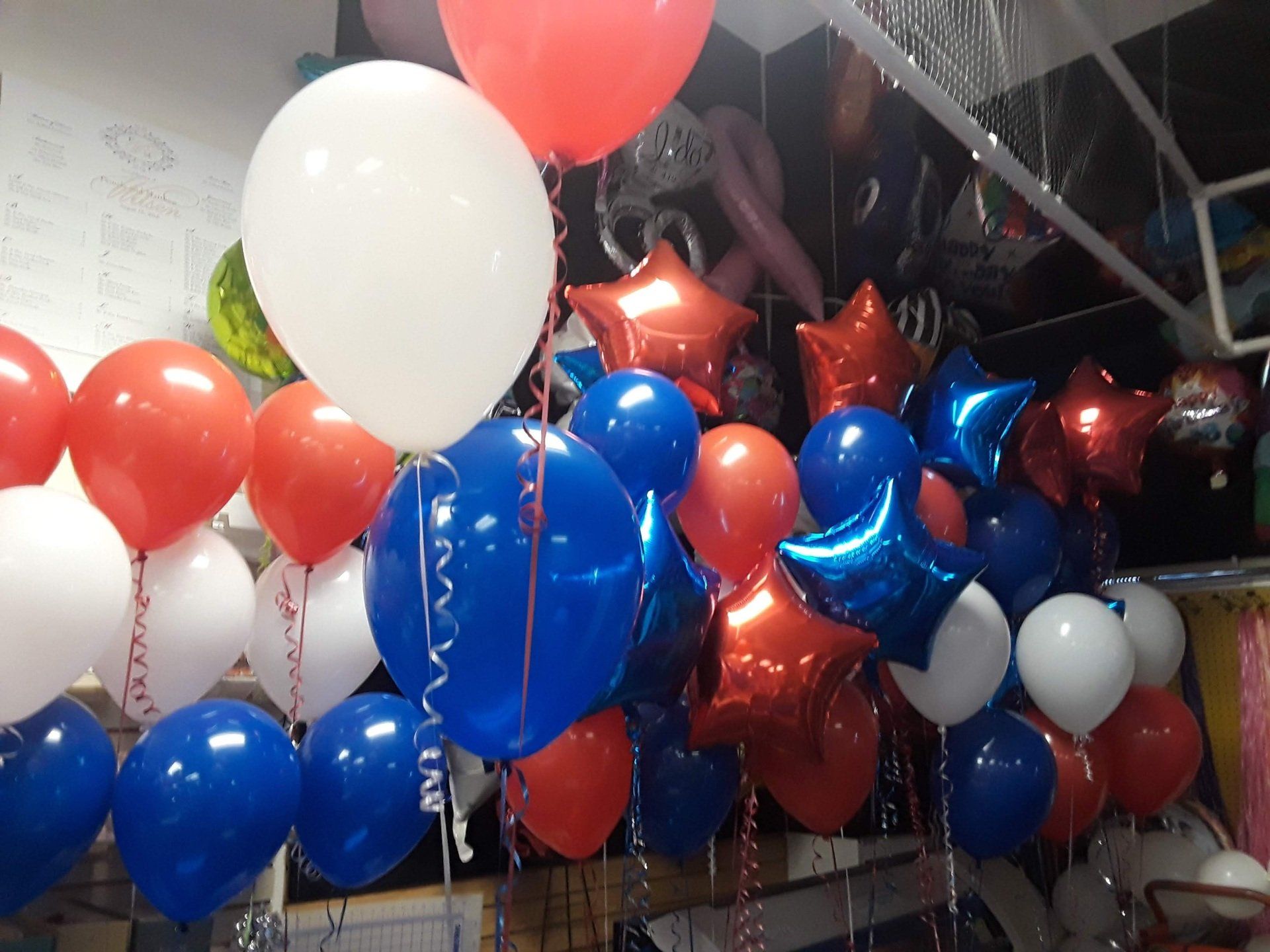 A bunch of red white and blue balloons hanging from the ceiling