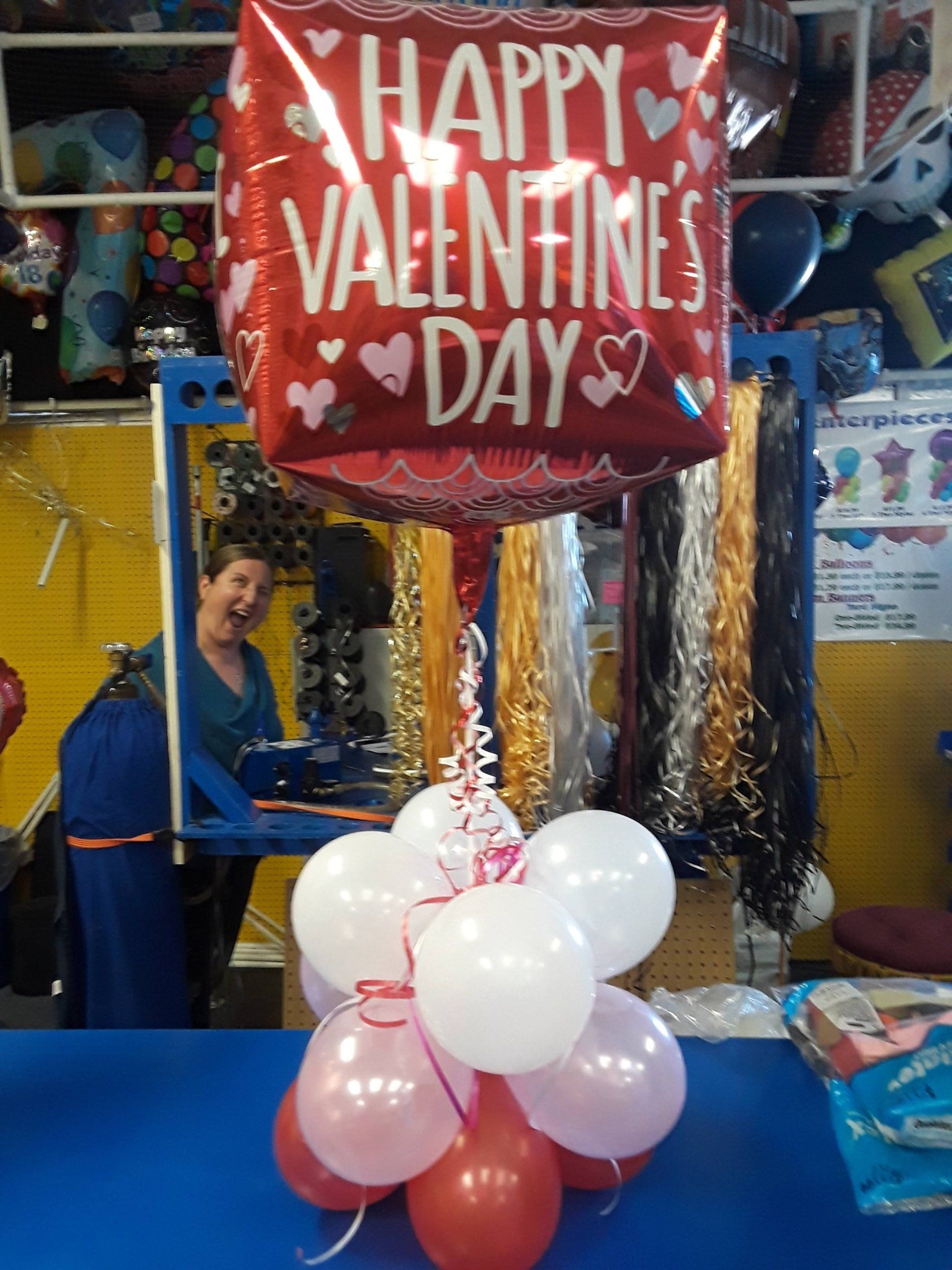 A red happy valentine 's day balloon surrounded by pink and white balloons