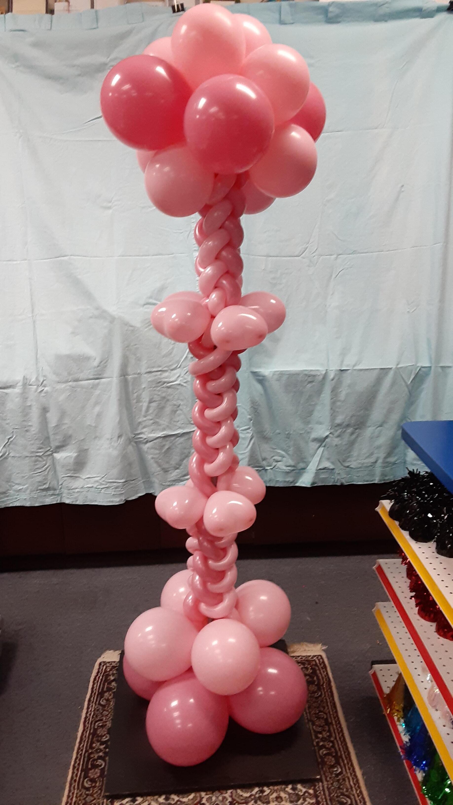 A bunch of pink balloons are stacked on top of each other on a table.