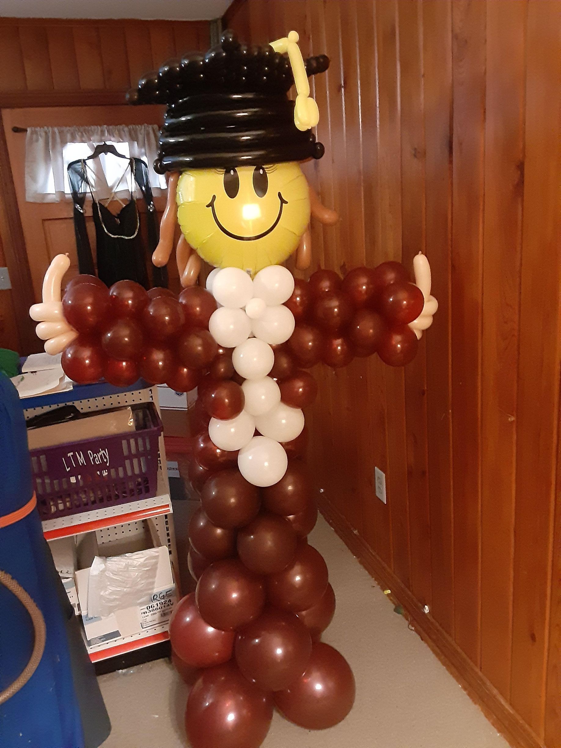 A balloon sculpture of a girl wearing a graduation cap and gown