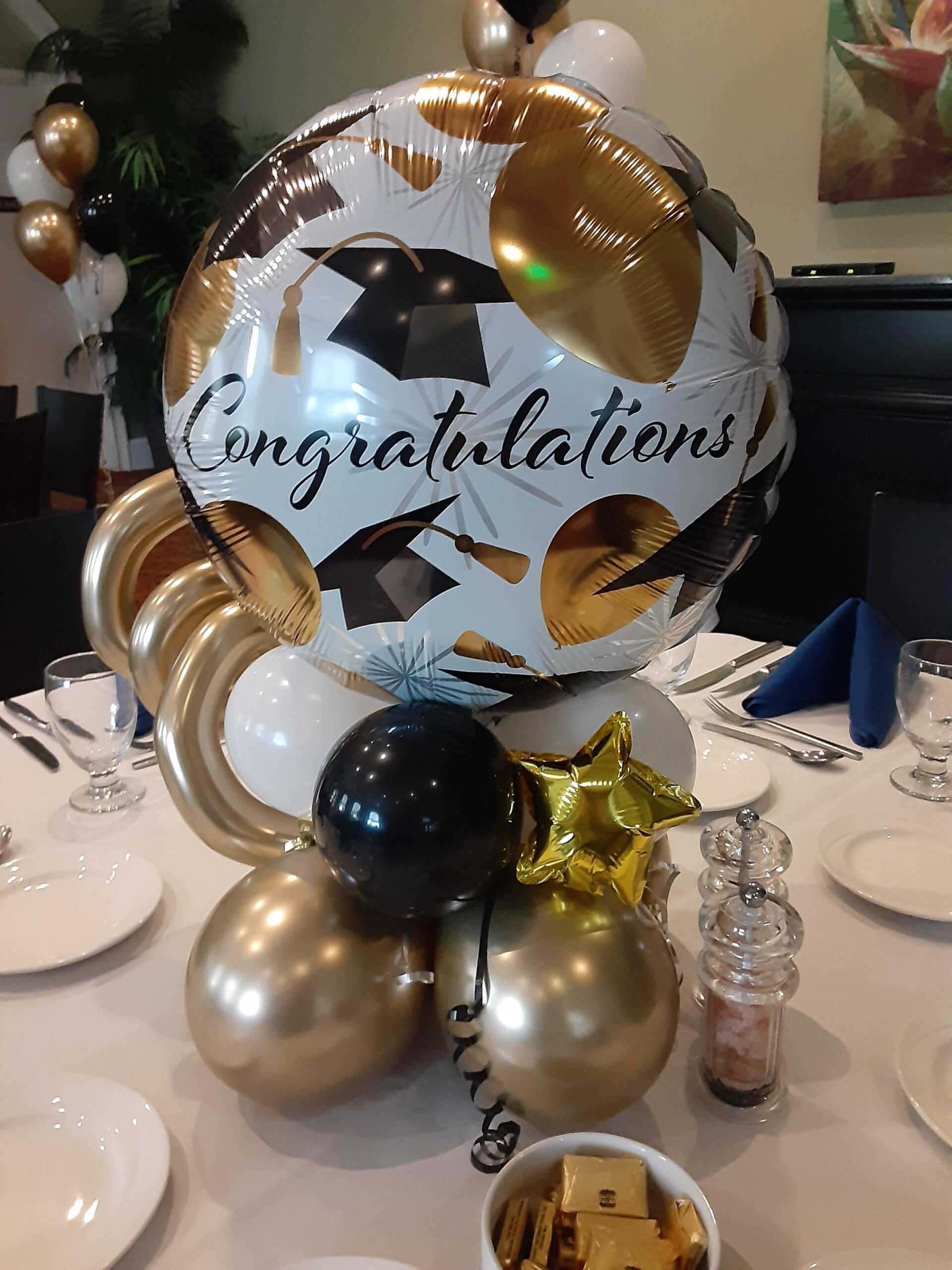 A congratulations balloon is surrounded by balloons on a table