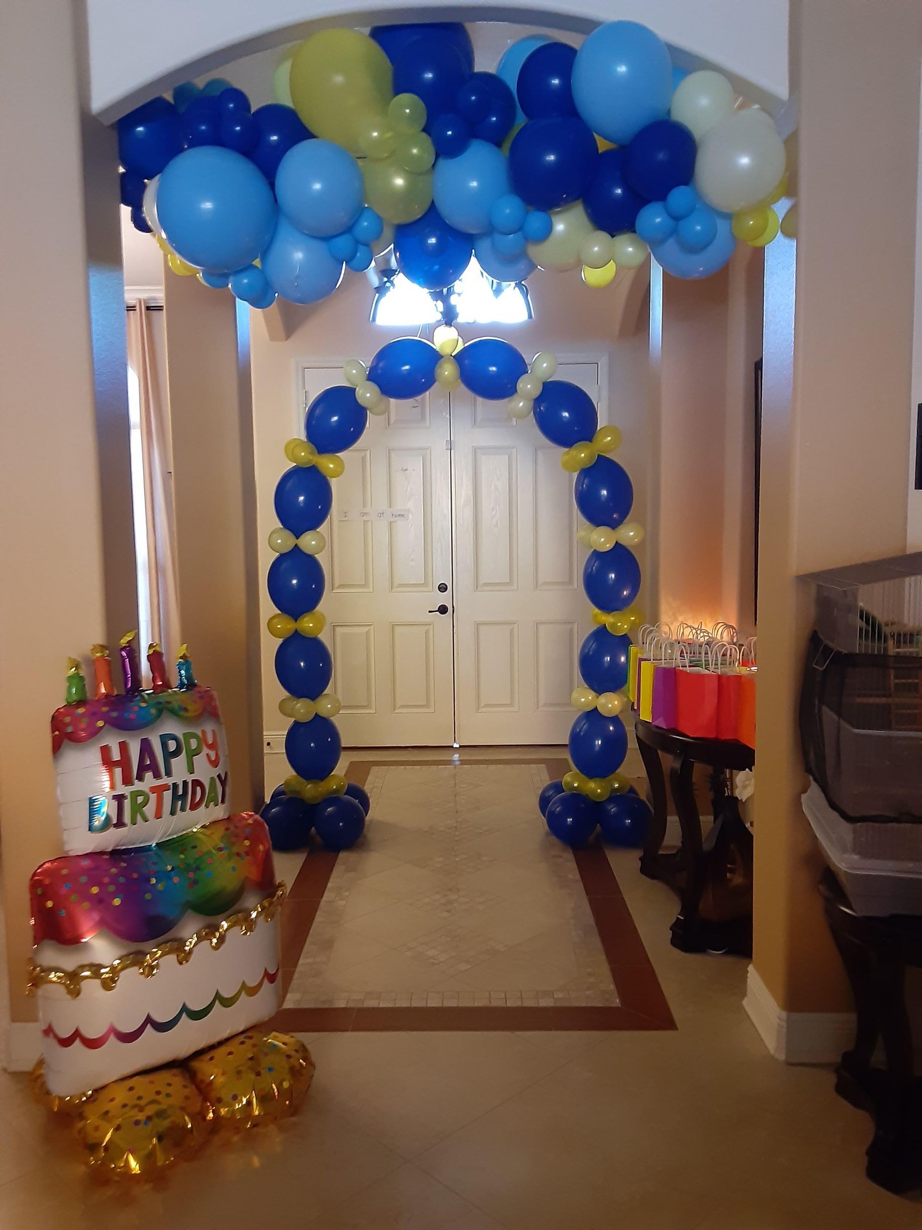 A hallway decorated with balloons and a cake that says happy birthday