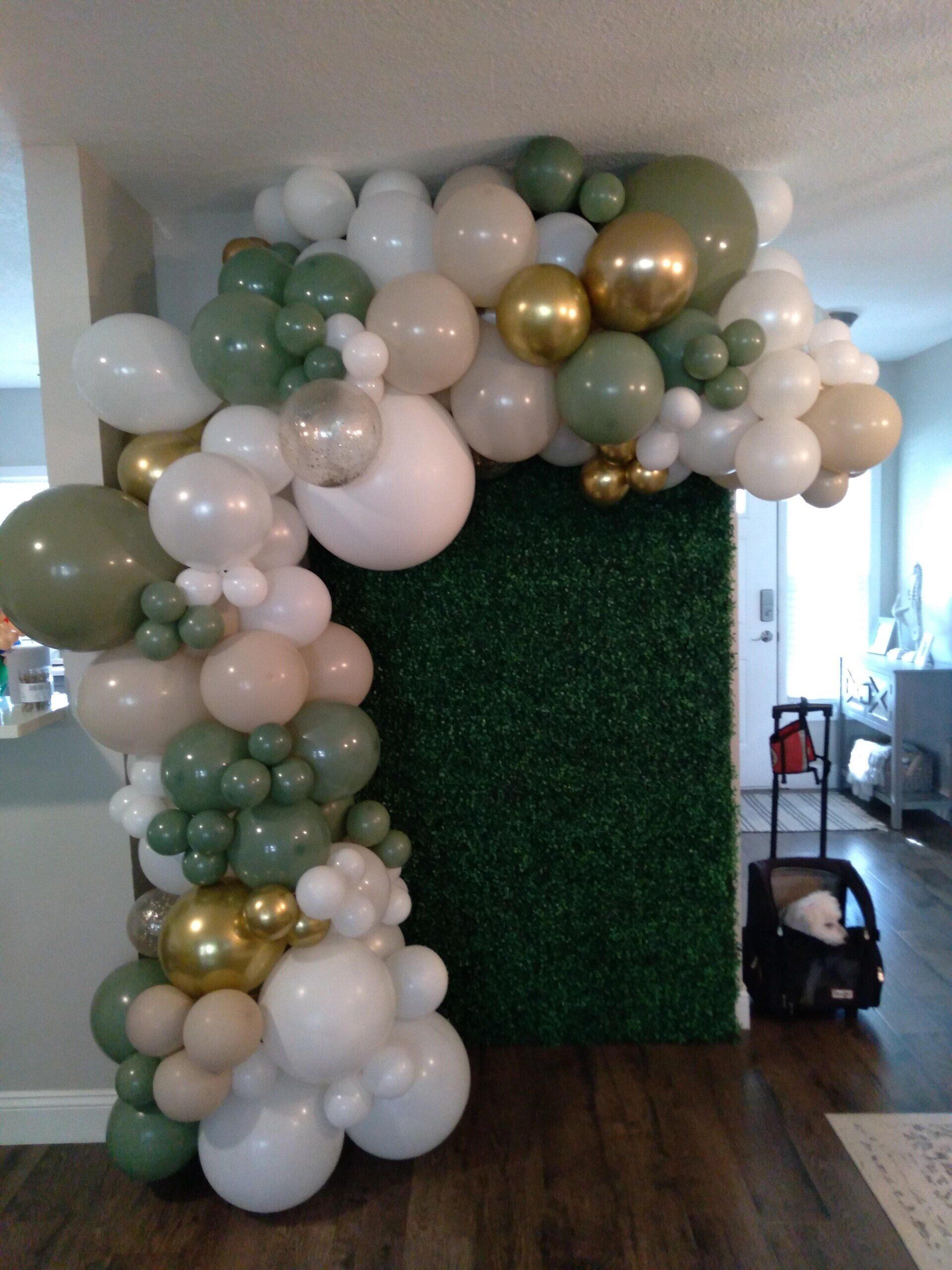 A bunch of balloons are sitting in front of a green wall