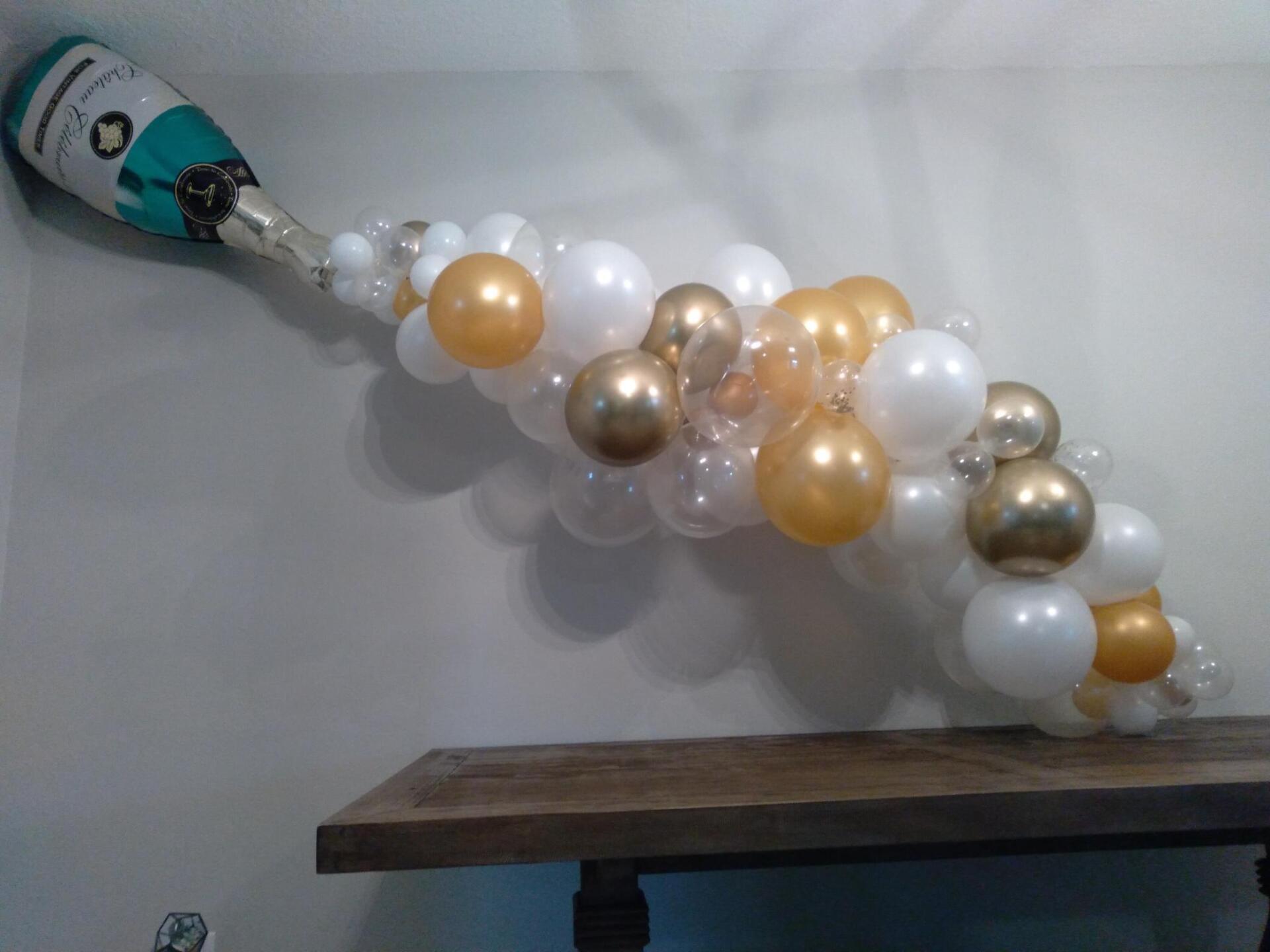 A bottle of champagne is being poured into a bunch of balloons.