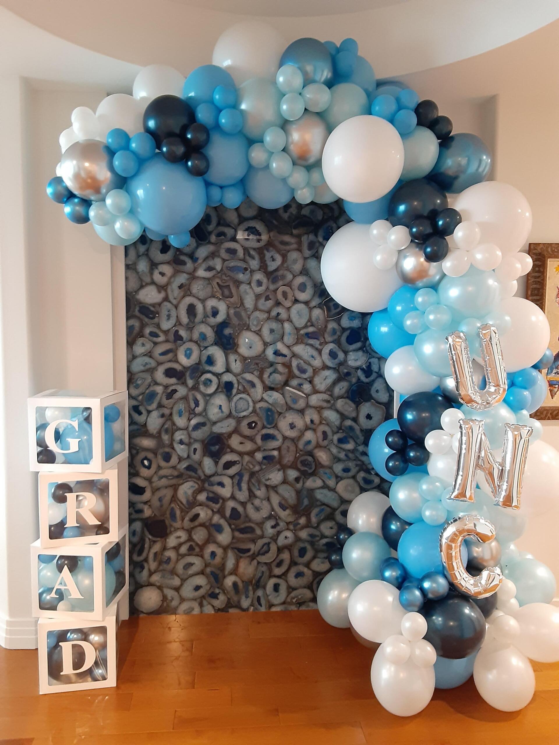 A room decorated with blue , white and silver balloons for a baby shower.