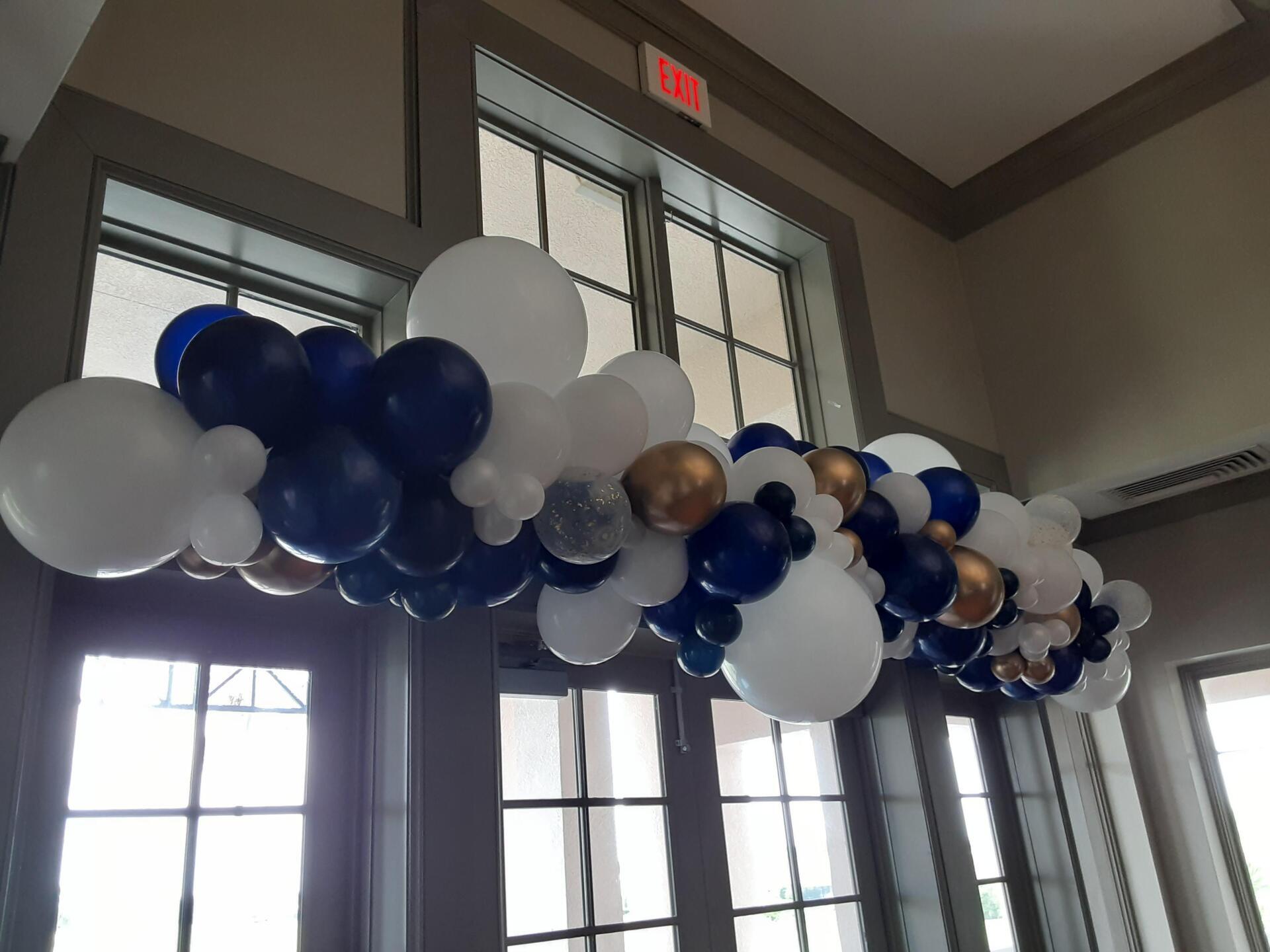 A bunch of blue and white balloons hanging from the ceiling