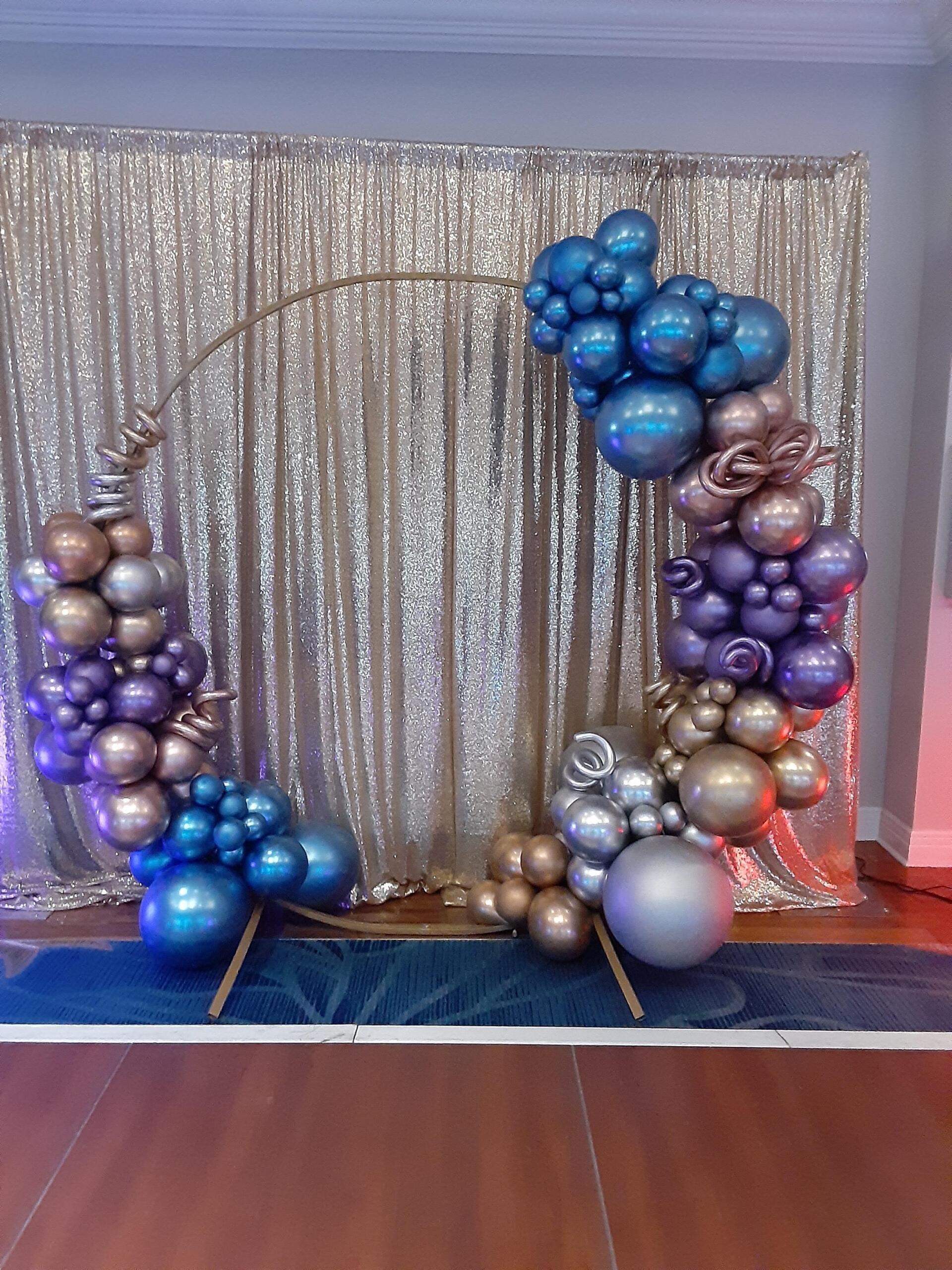 A room filled with balloons and a sequined curtain.