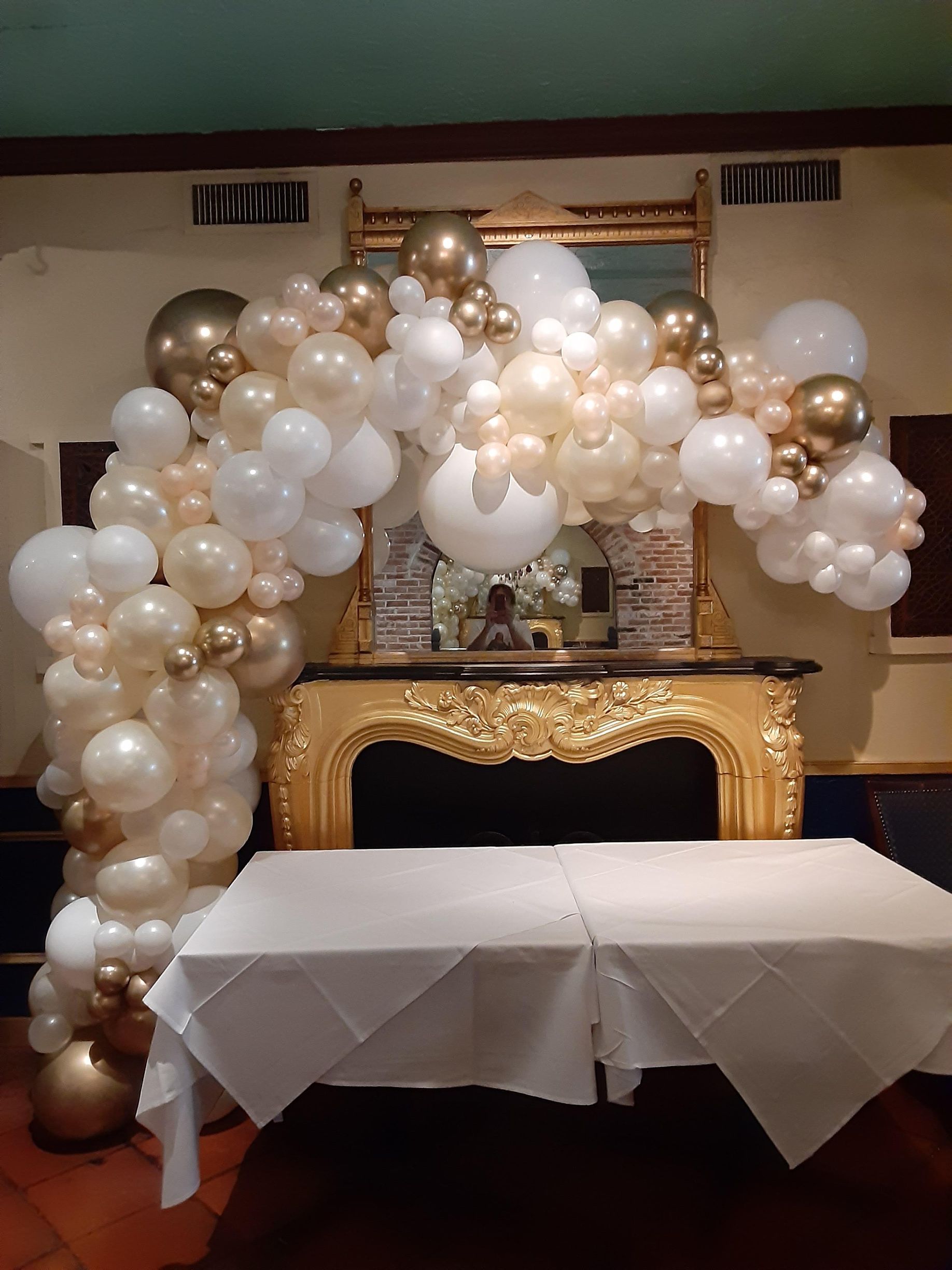 A room with a table and a fireplace decorated with balloons.