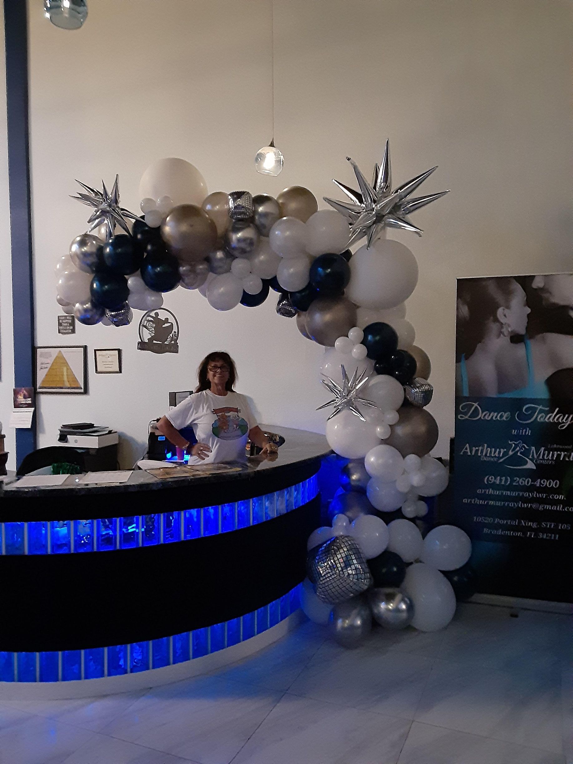A woman is standing behind a counter decorated with balloons.