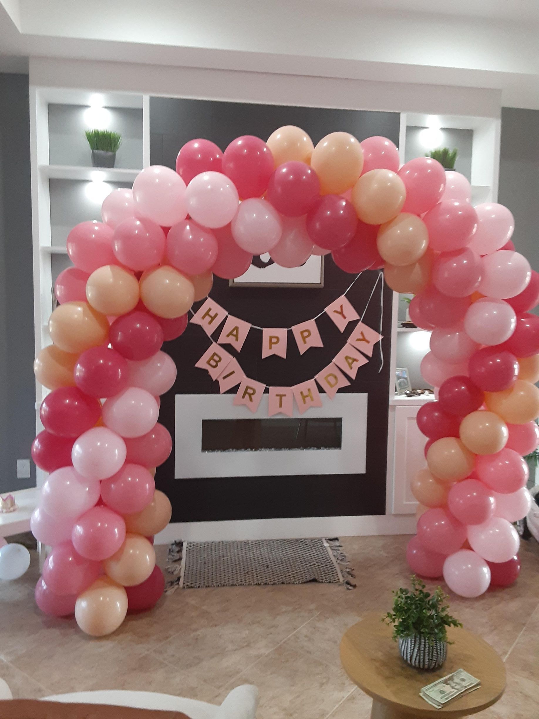 A room decorated with pink and orange balloons and a happy birthday banner