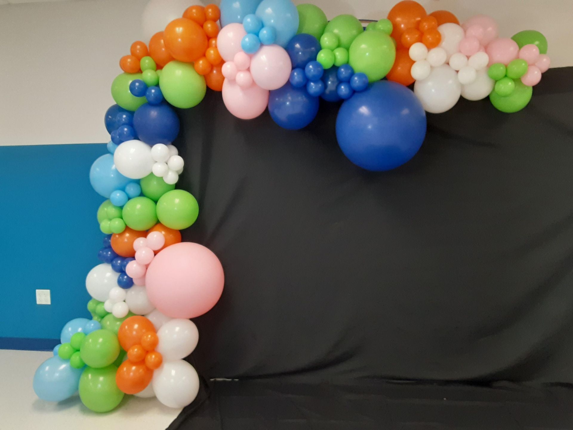 A bunch of colorful balloons are sitting on a black cloth.