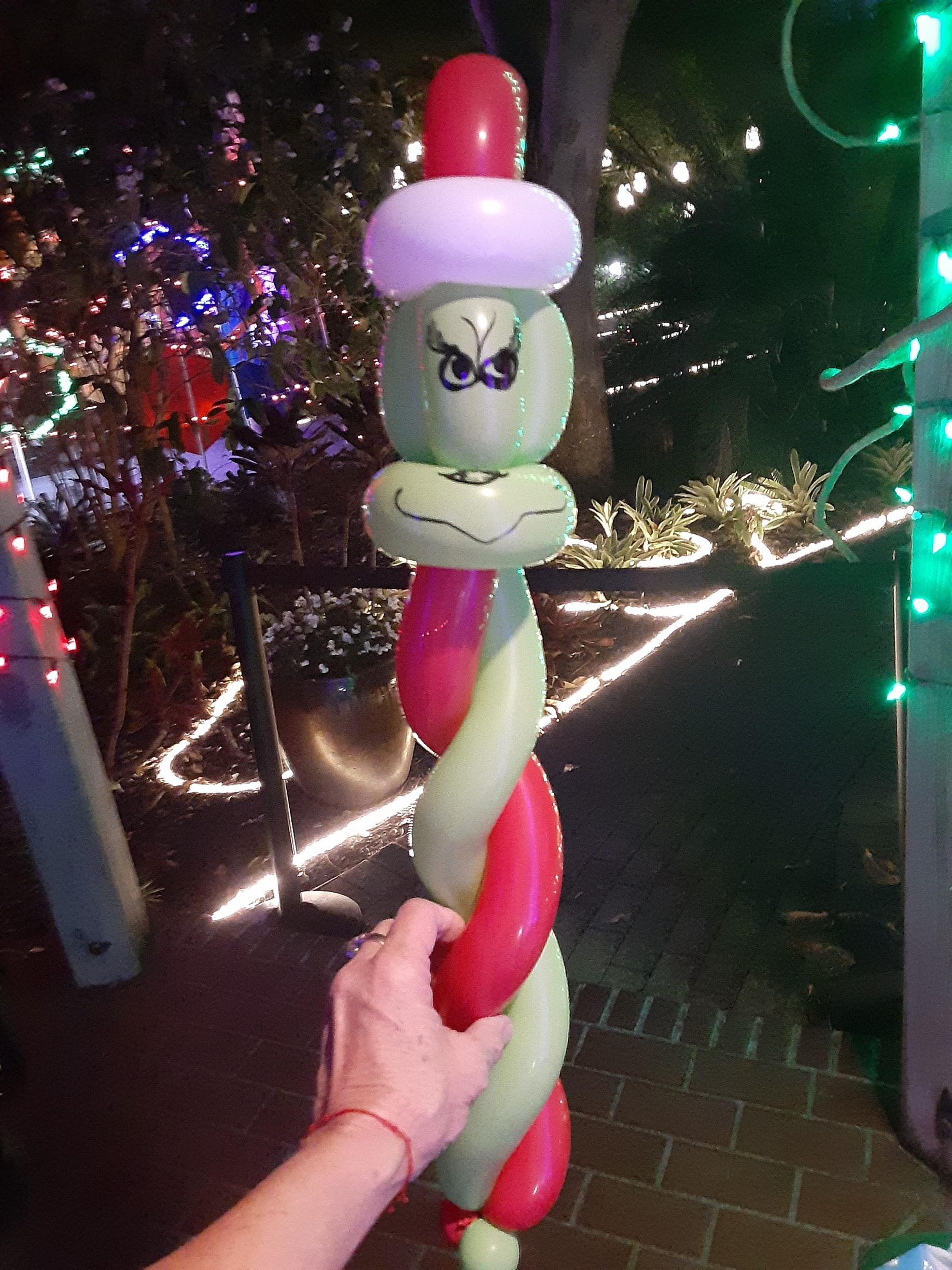 A person is holding a balloon that looks like the grinch.