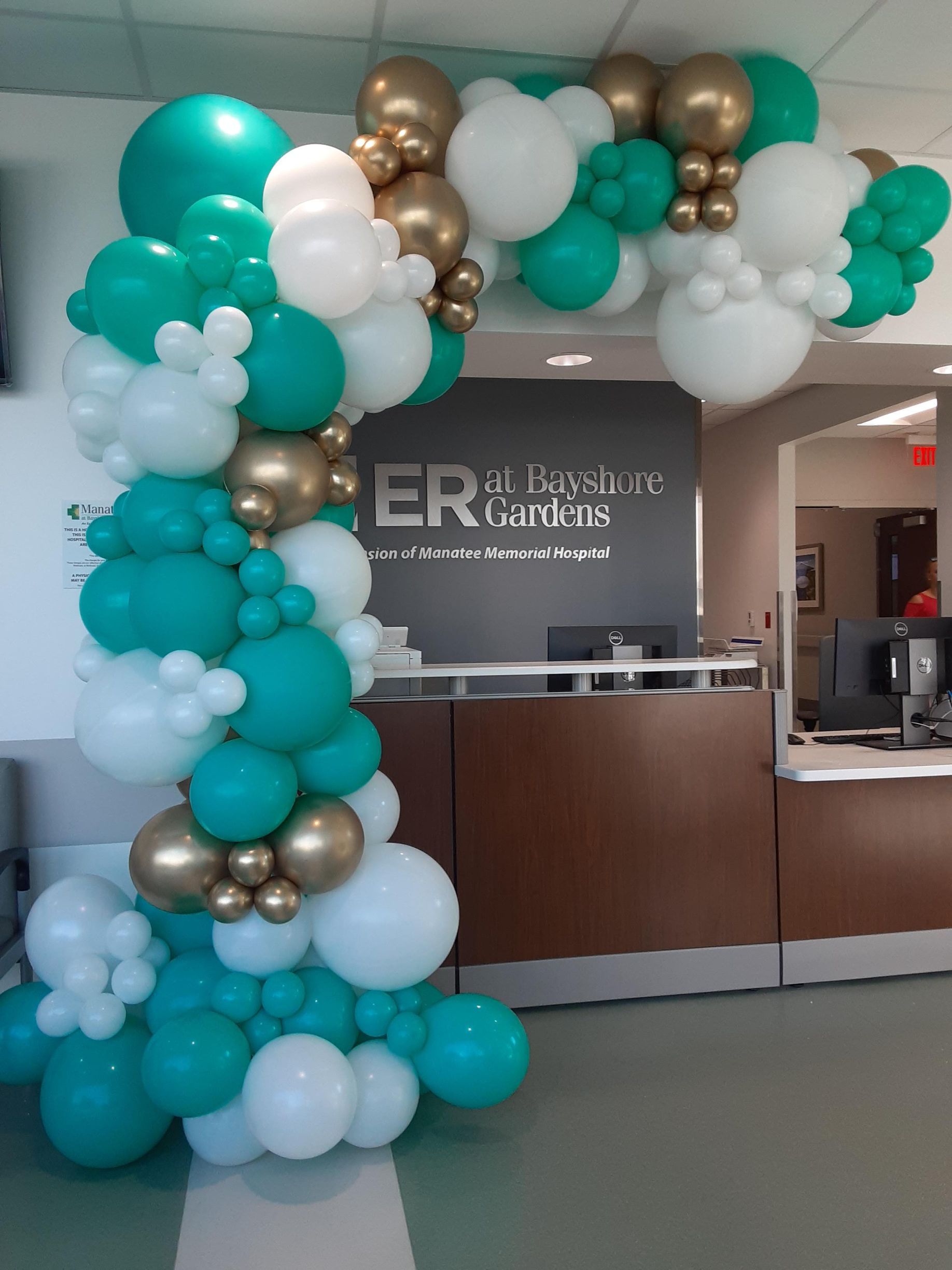 A bunch of green white and gold balloons in front of a sign that says er