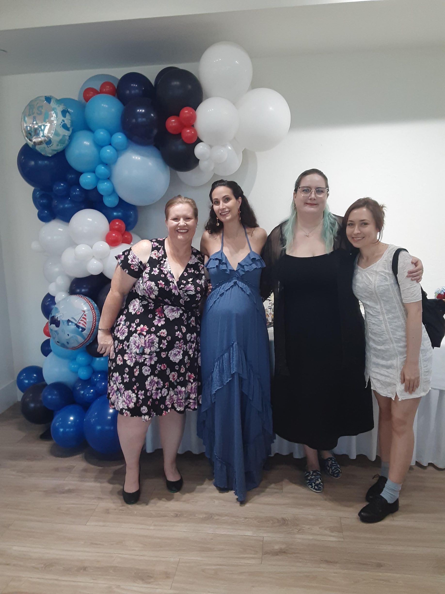A group of women are posing for a picture in front of balloons.