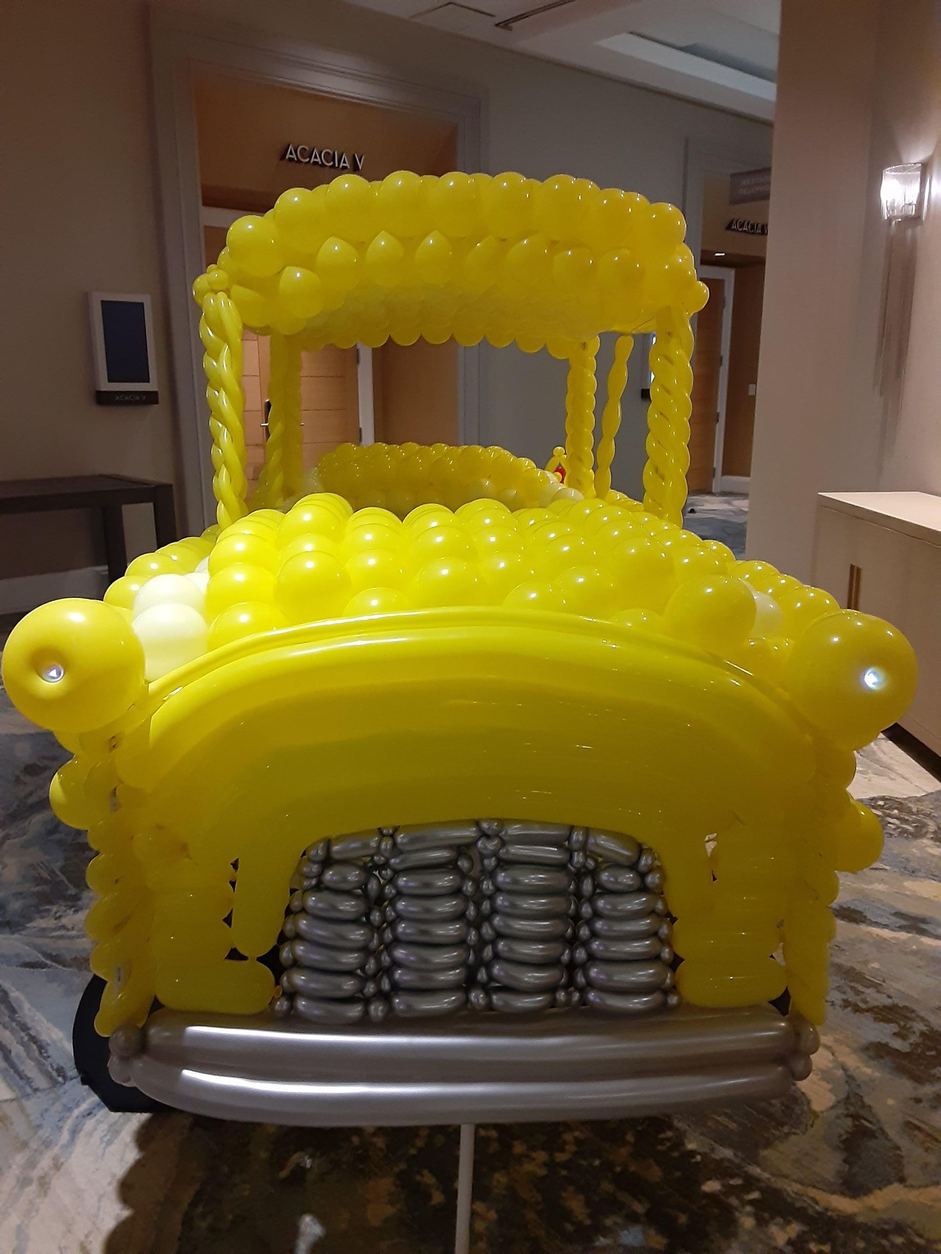 A yellow school bus made out of balloons is sitting on a table.