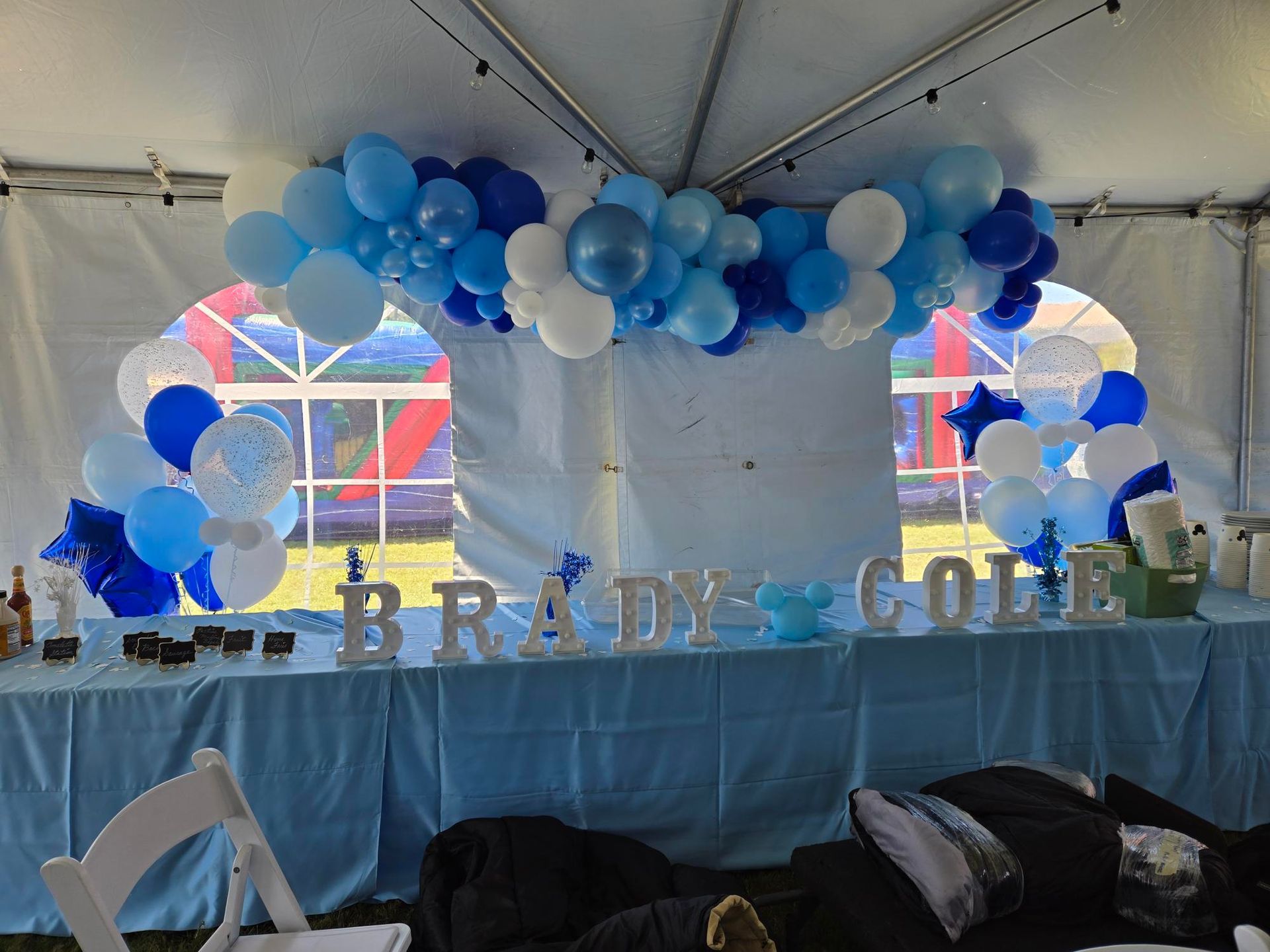 A table with balloons and letters on it under a tent.