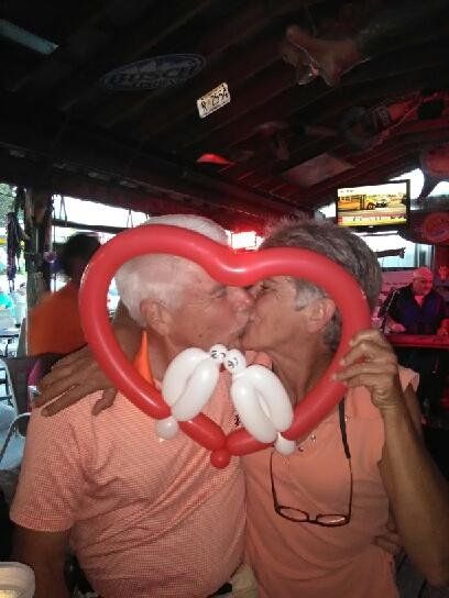 A man and woman kissing behind a heart shaped balloon