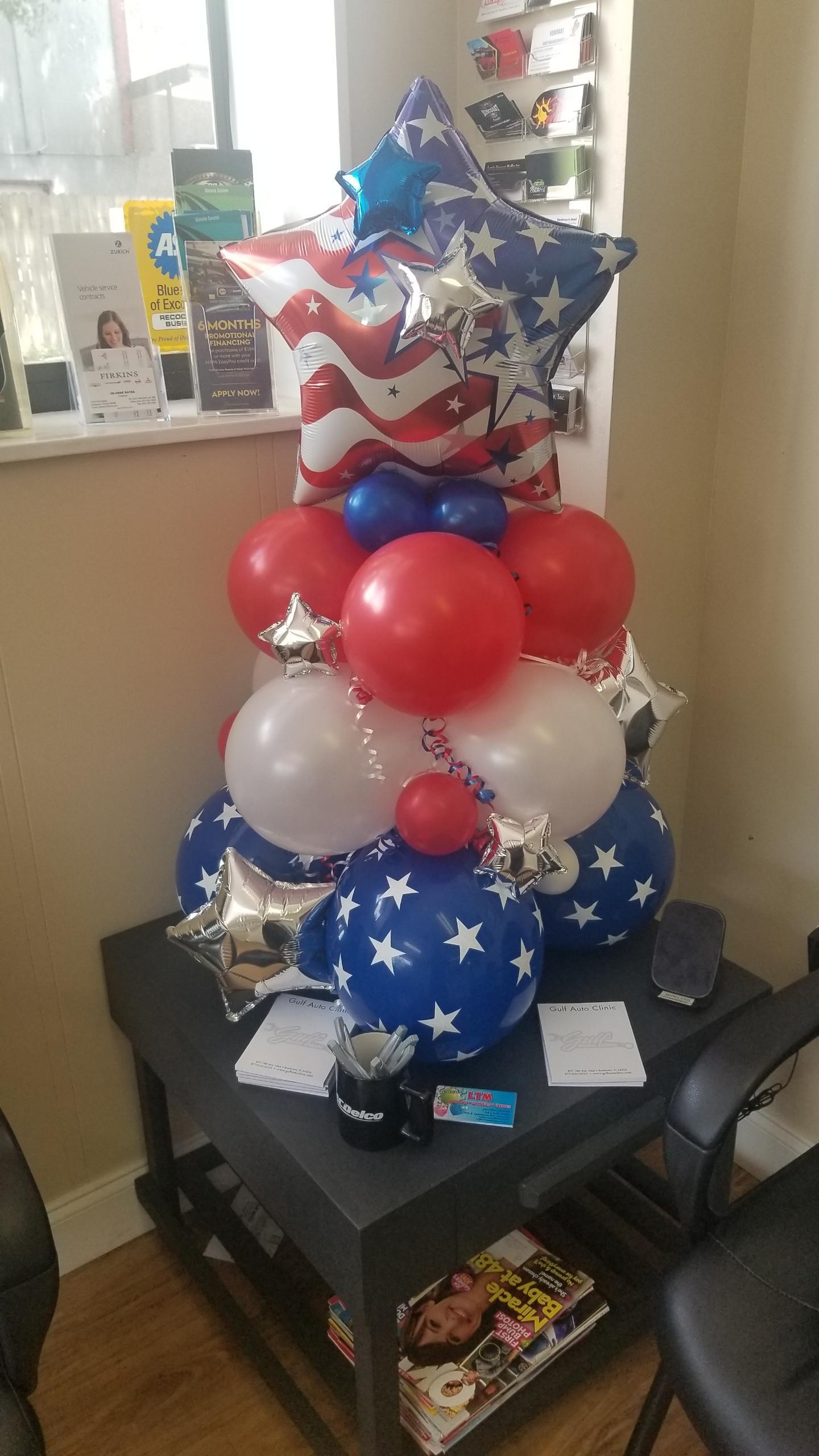 A stack of red , white , and blue balloons on a table.