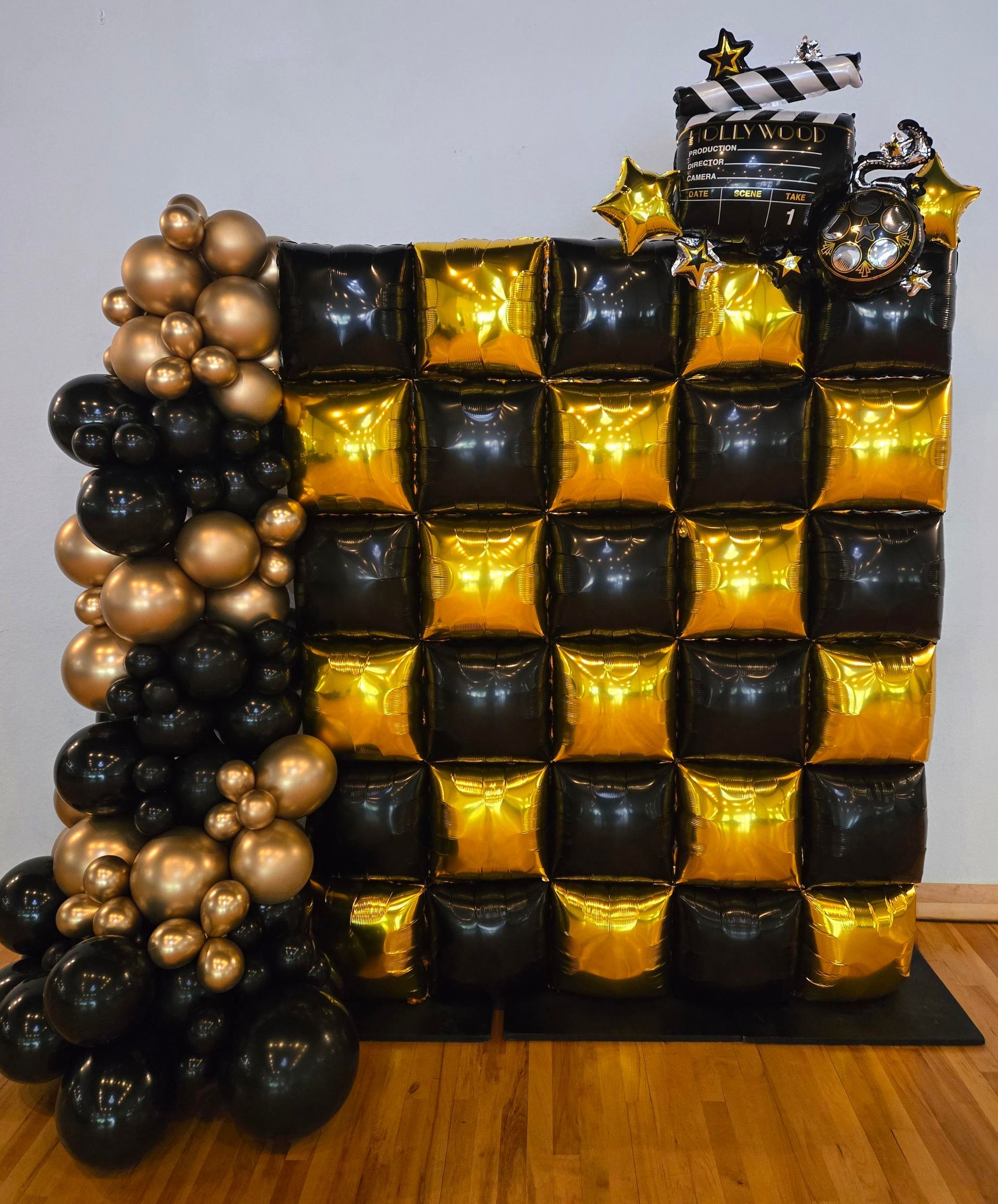 Black and gold balloon backdrop for a Hollywood theme party with a checkerboard design and film reel.