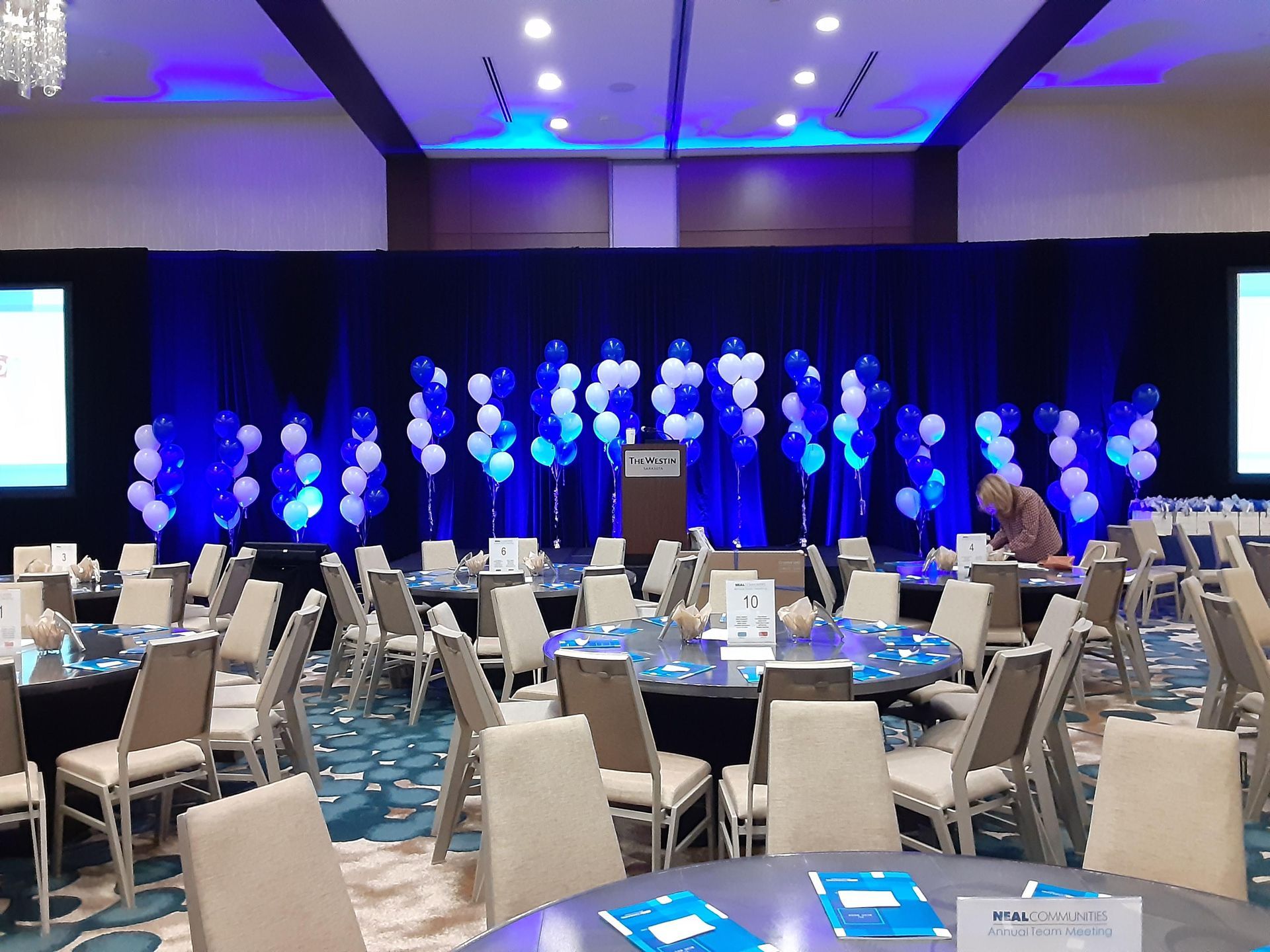 A large room with tables and chairs and balloons on the wall.