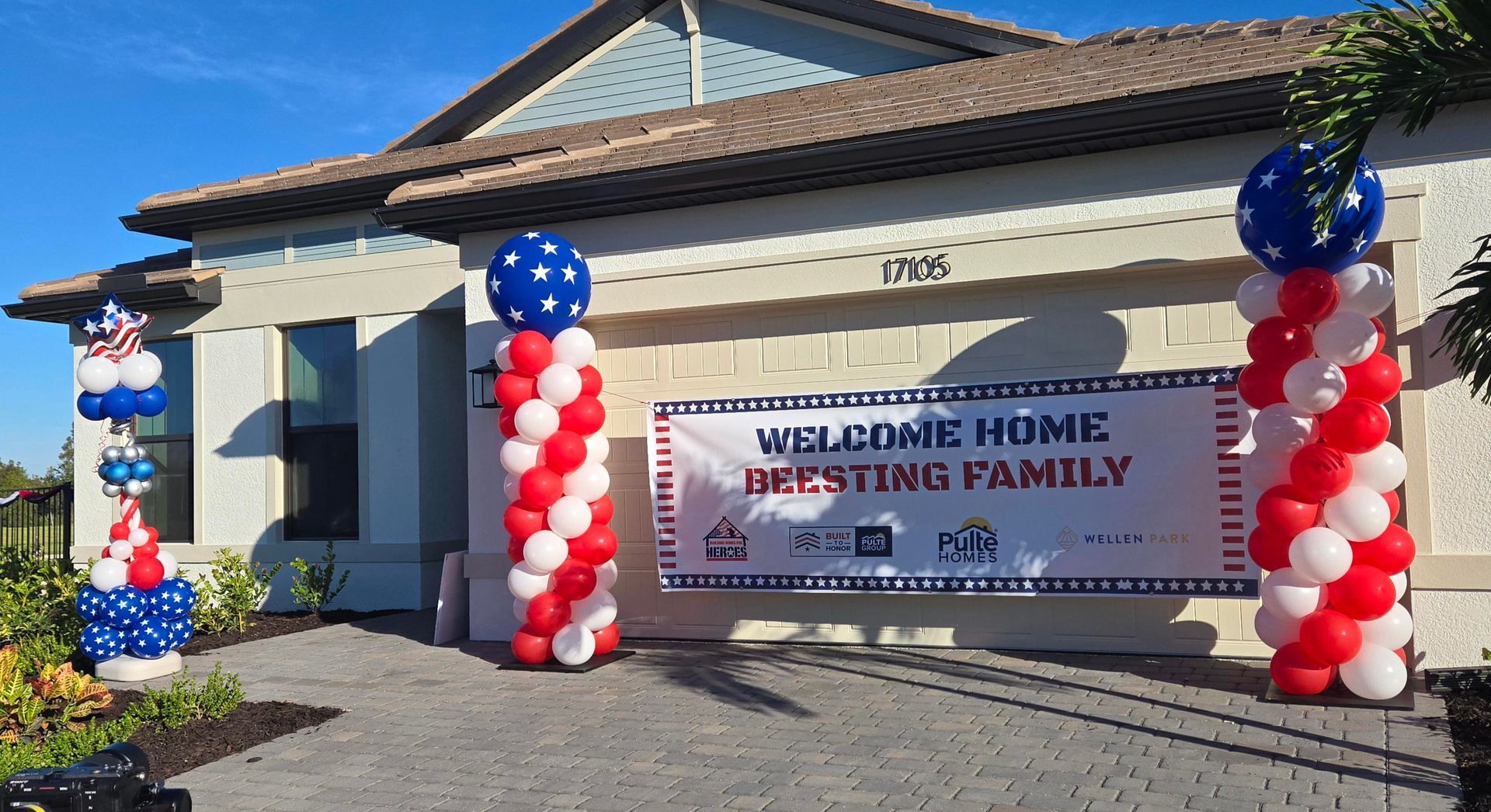 House decorated with red, white, and blue balloons for a welcome home banner.