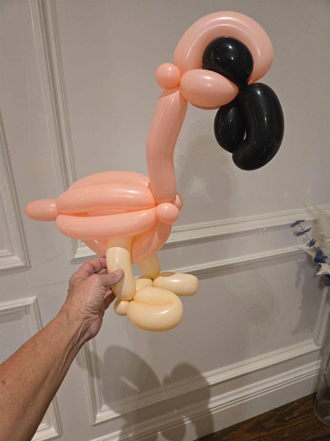 A person is holding a flamingo made out of balloons.