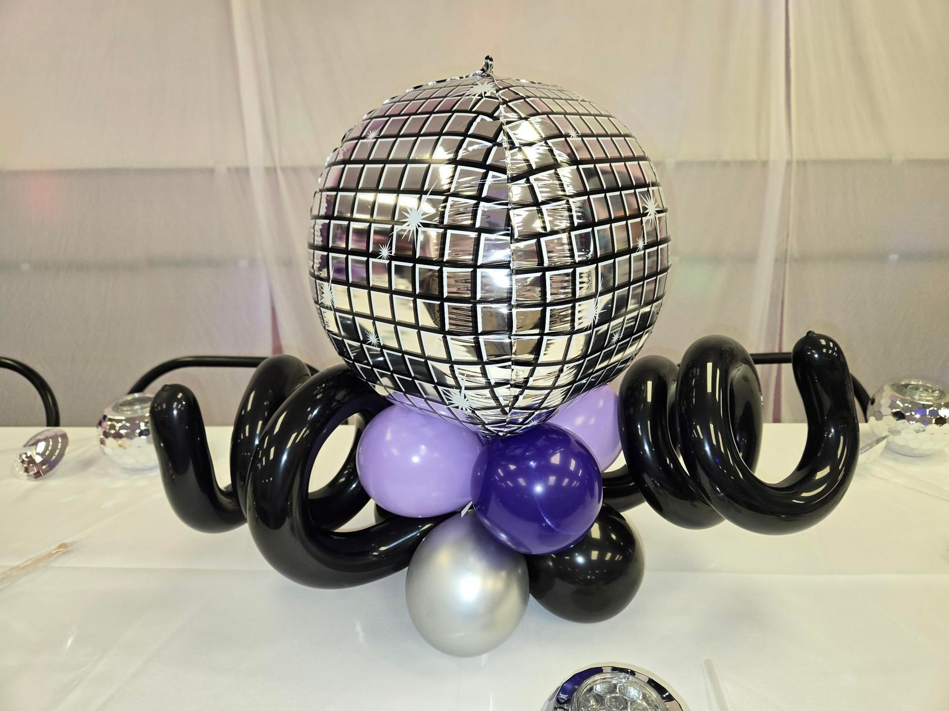 Disco ball centerpiece with black, purple, and silver balloons