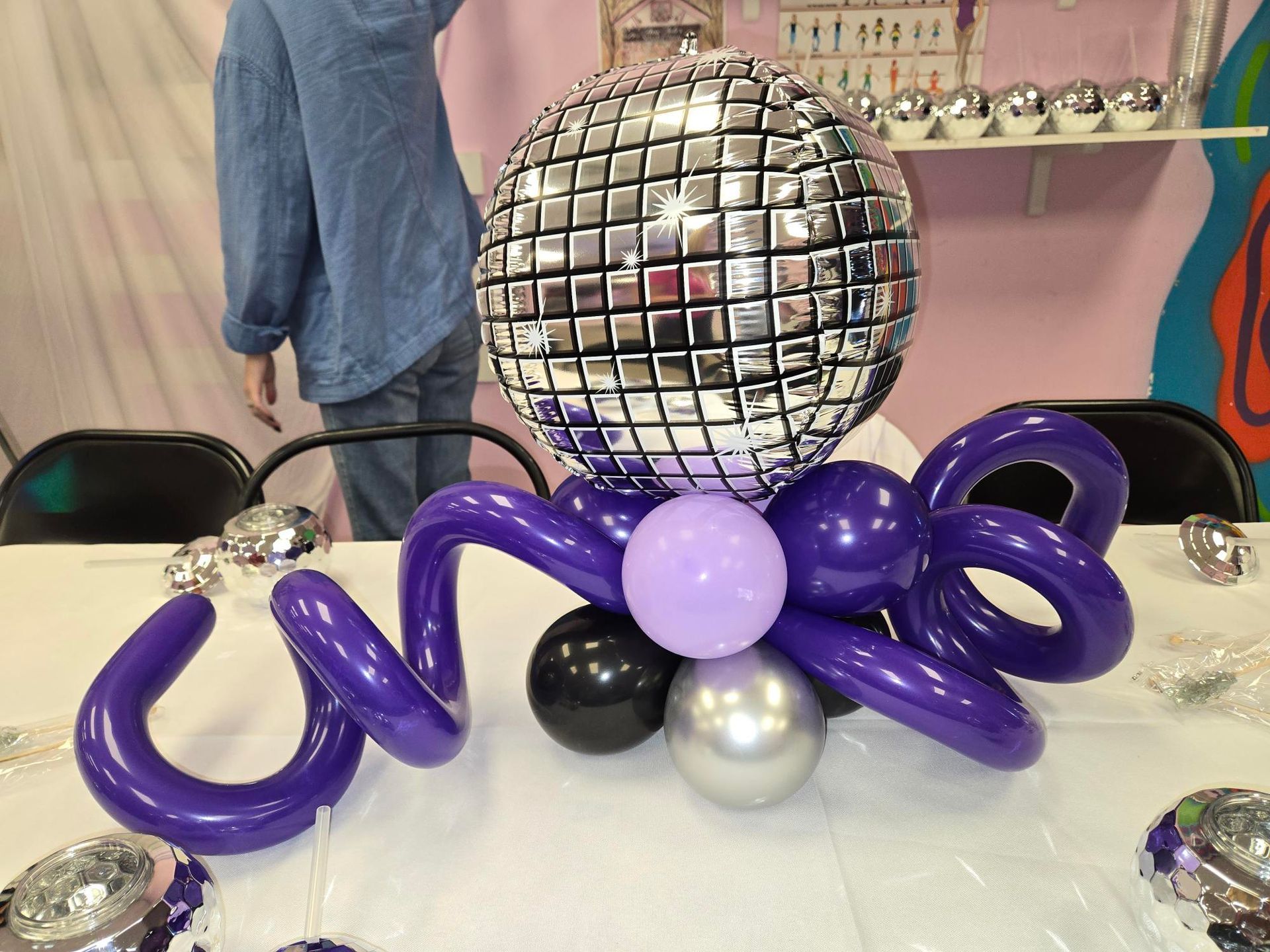 Disco ball centerpiece with purple balloons on a table