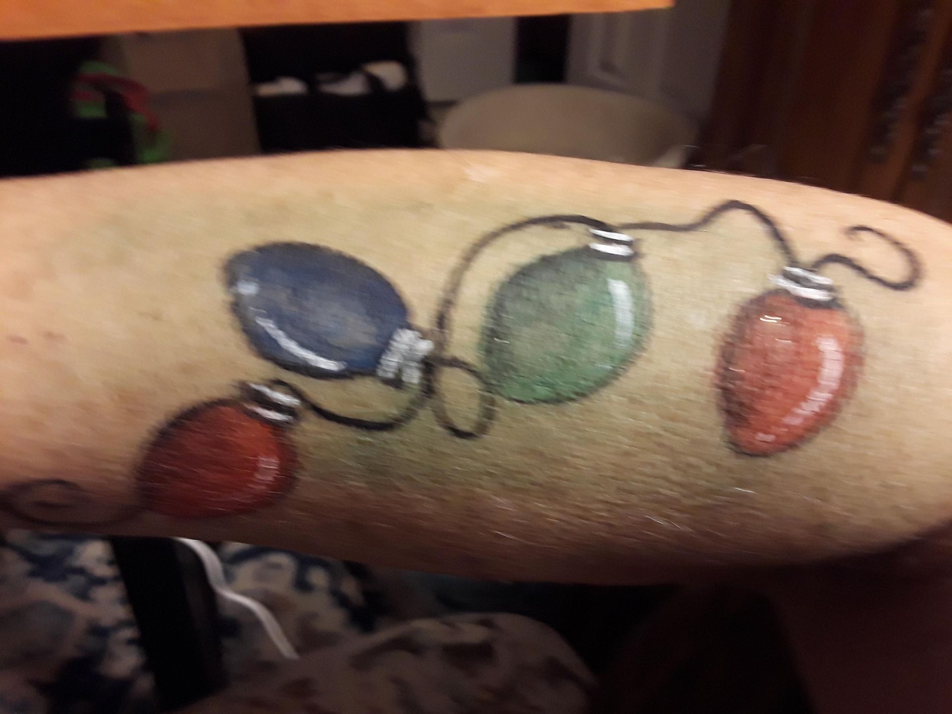 Paint tattoo of colorful Christmas lights on a person's arm