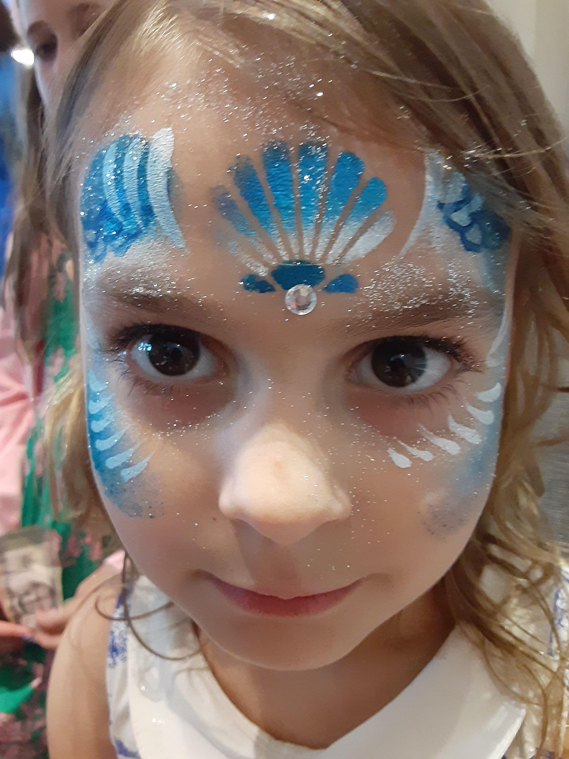 Girl with blue and white face paint, sparkly design