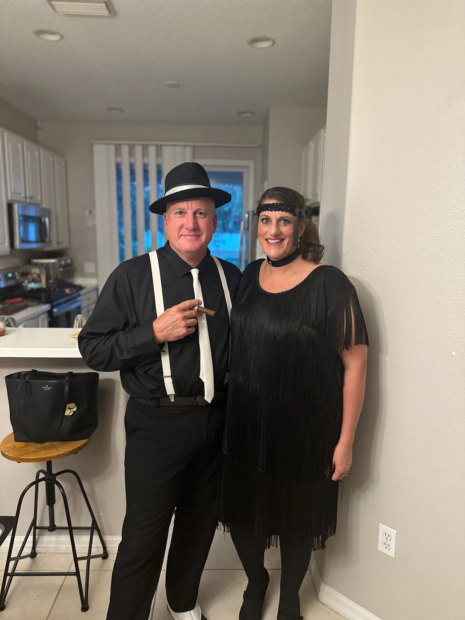 Couple in black and white 1920s costumes posing indoors