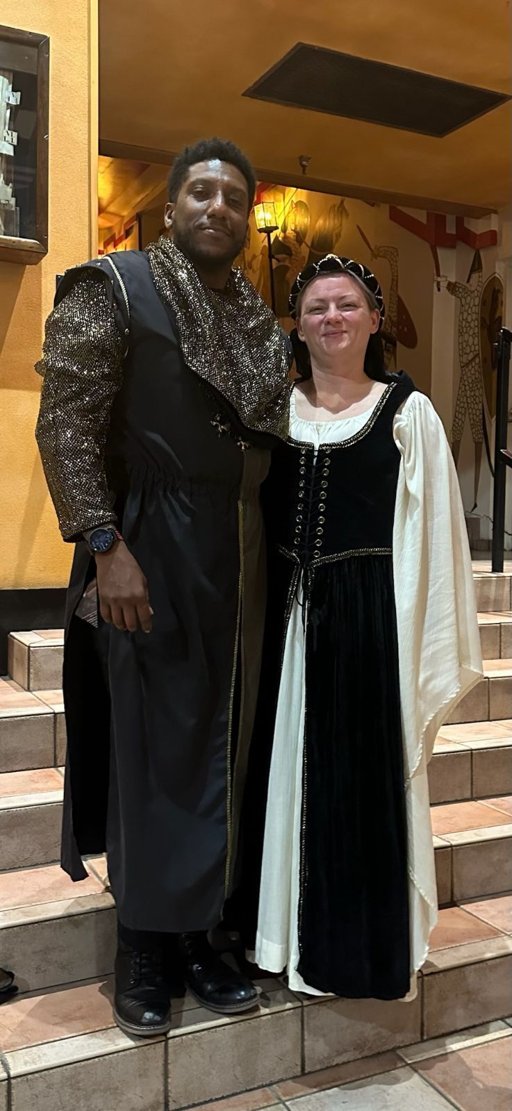 Two people in Renaissance costumes stand on stairs
